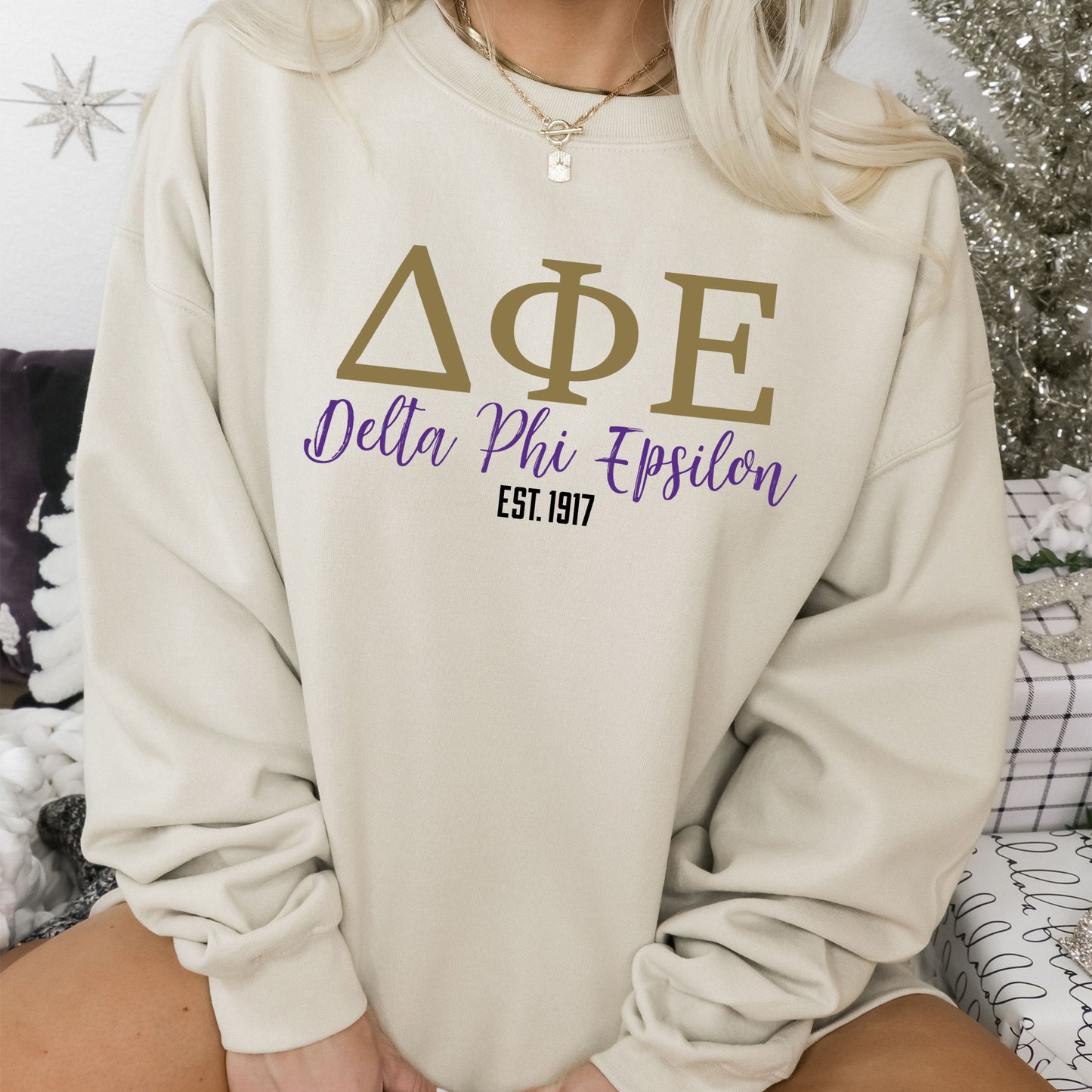 a woman sitting on a bed wearing a sweatshirt