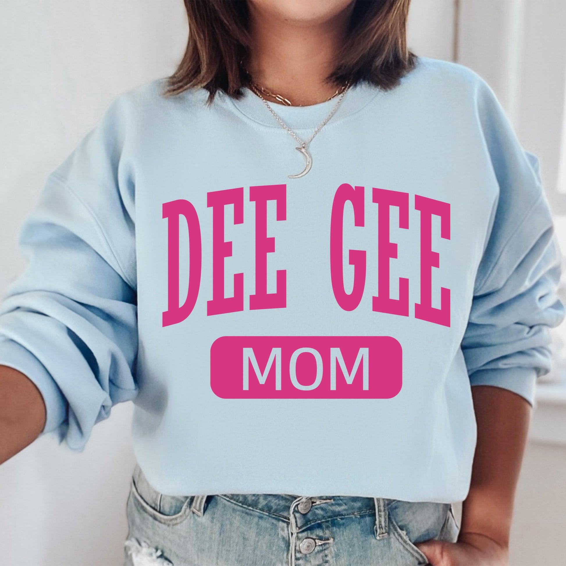 a woman wearing a sweatshirt that says dee gee mom