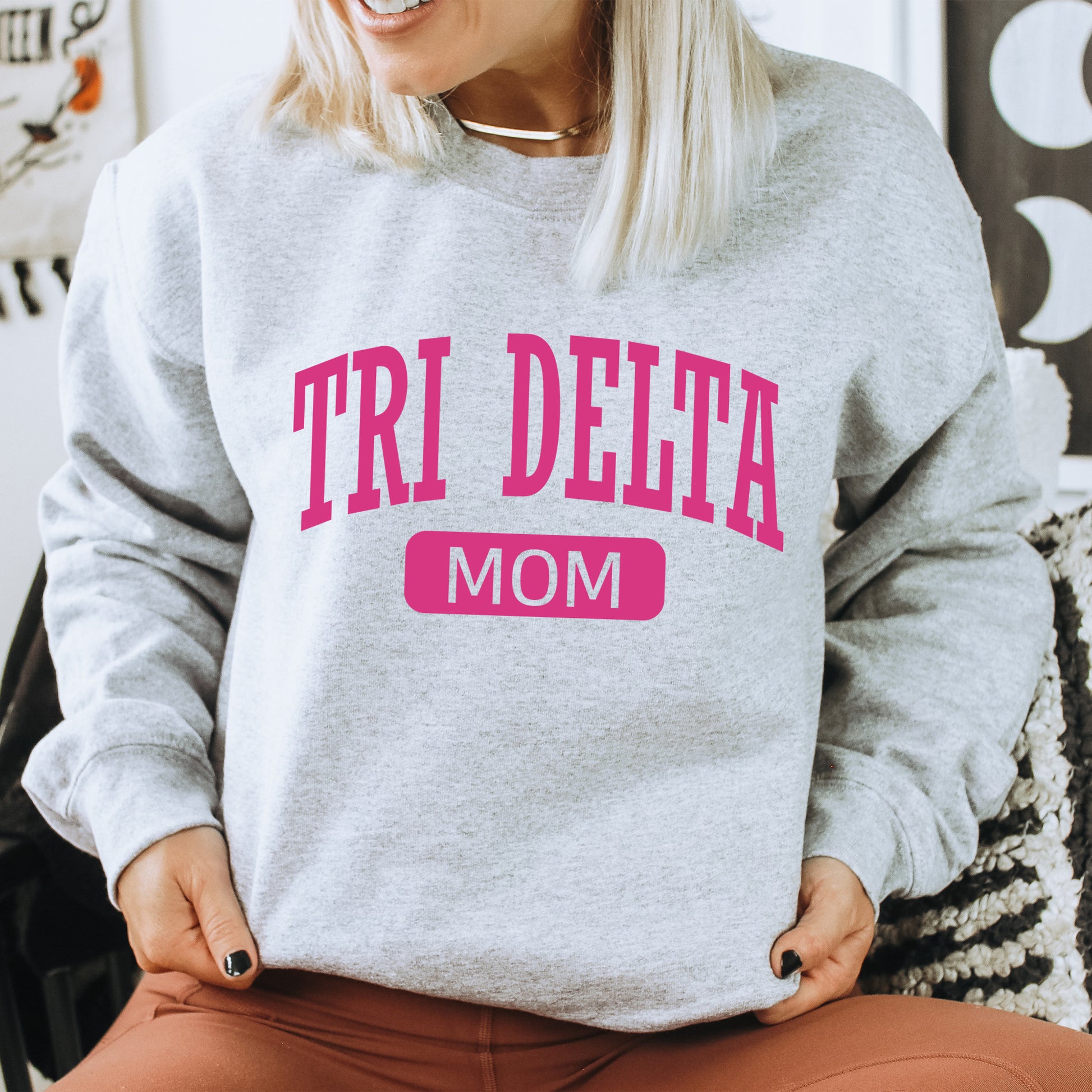 a woman wearing a sweatshirt that says tri delta mom