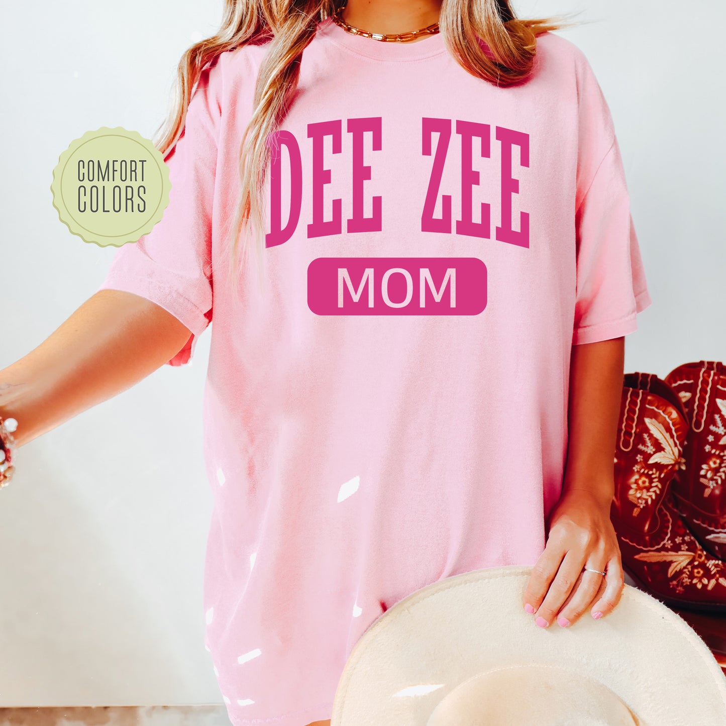 a woman wearing a pink shirt that says dee zeee mom