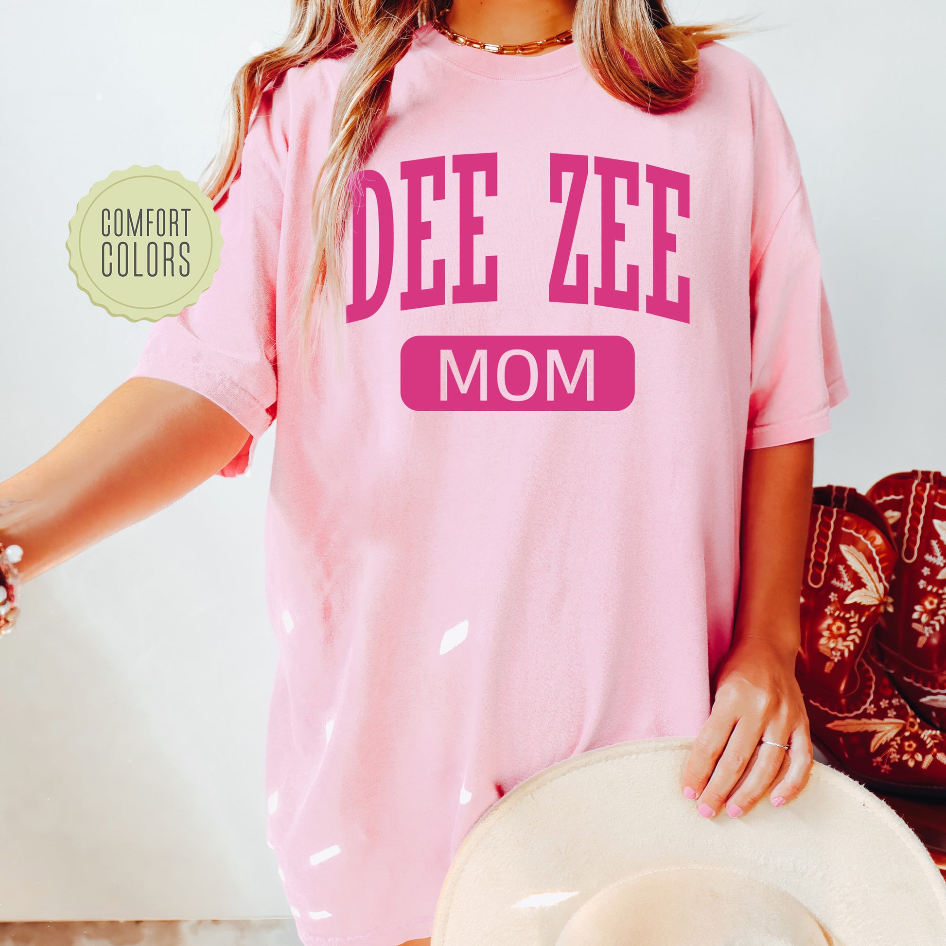 a woman wearing a pink shirt that says dee zeee mom