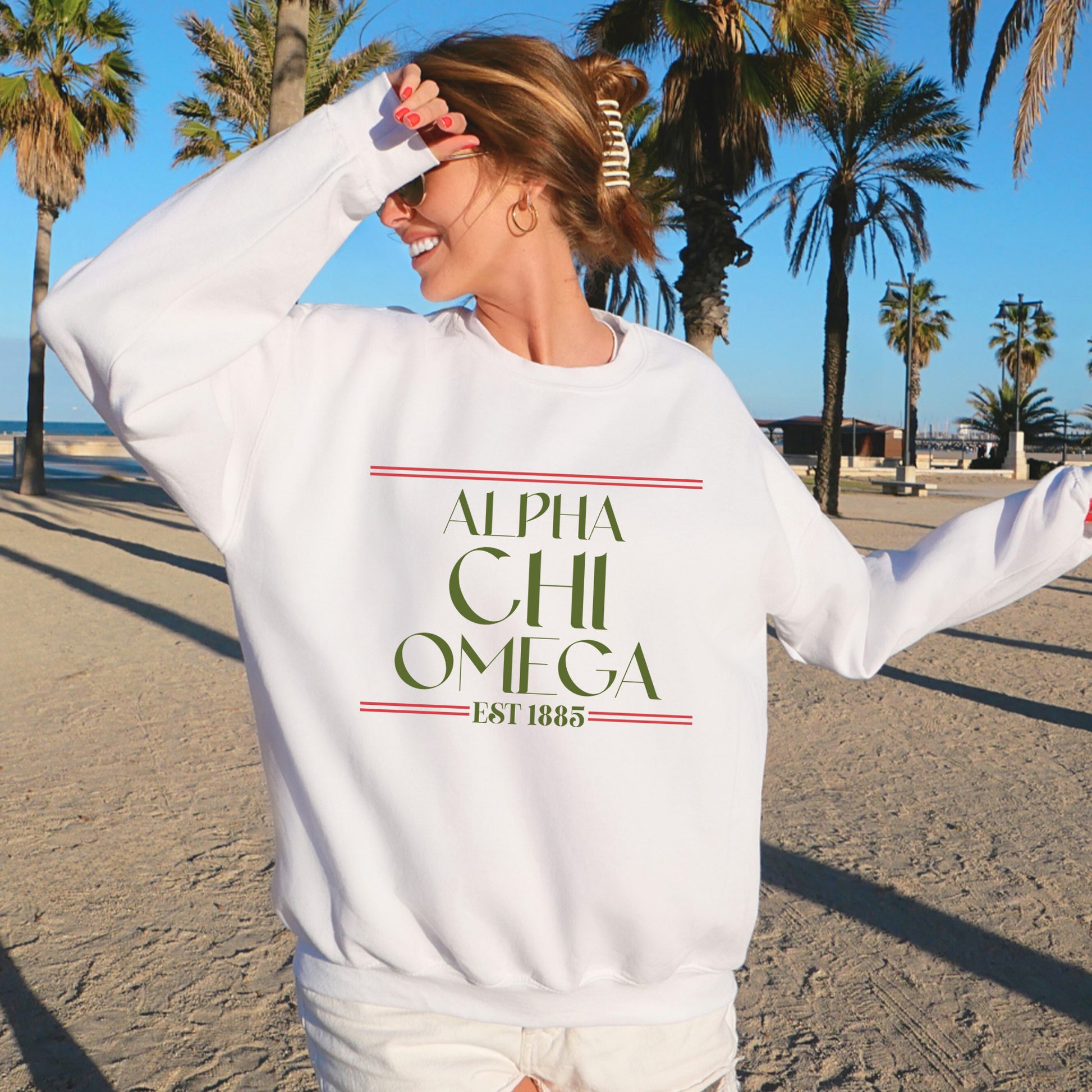 a woman standing on a beach wearing a white sweatshirt