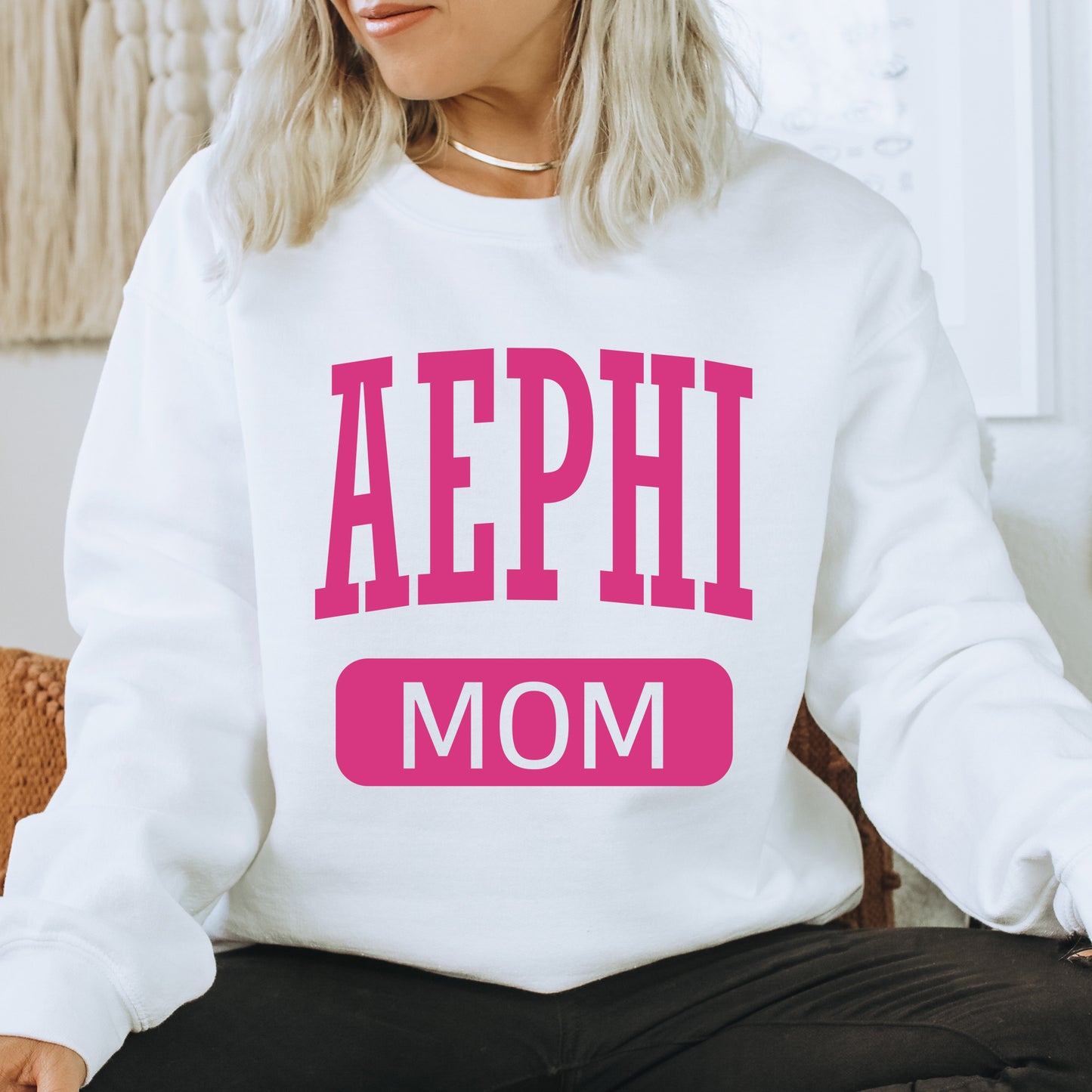 a woman wearing a sweatshirt that says aephi mom