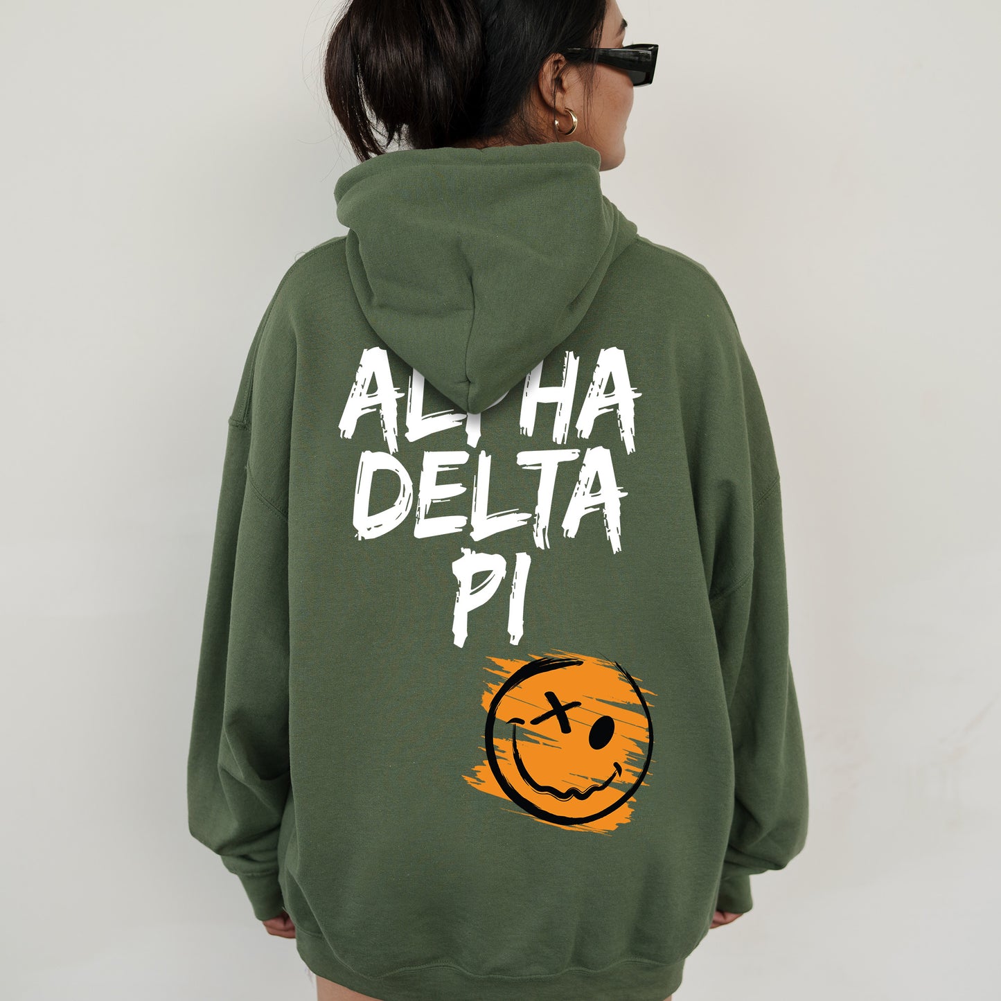 a woman wearing a green hoodie with a smiley face on it