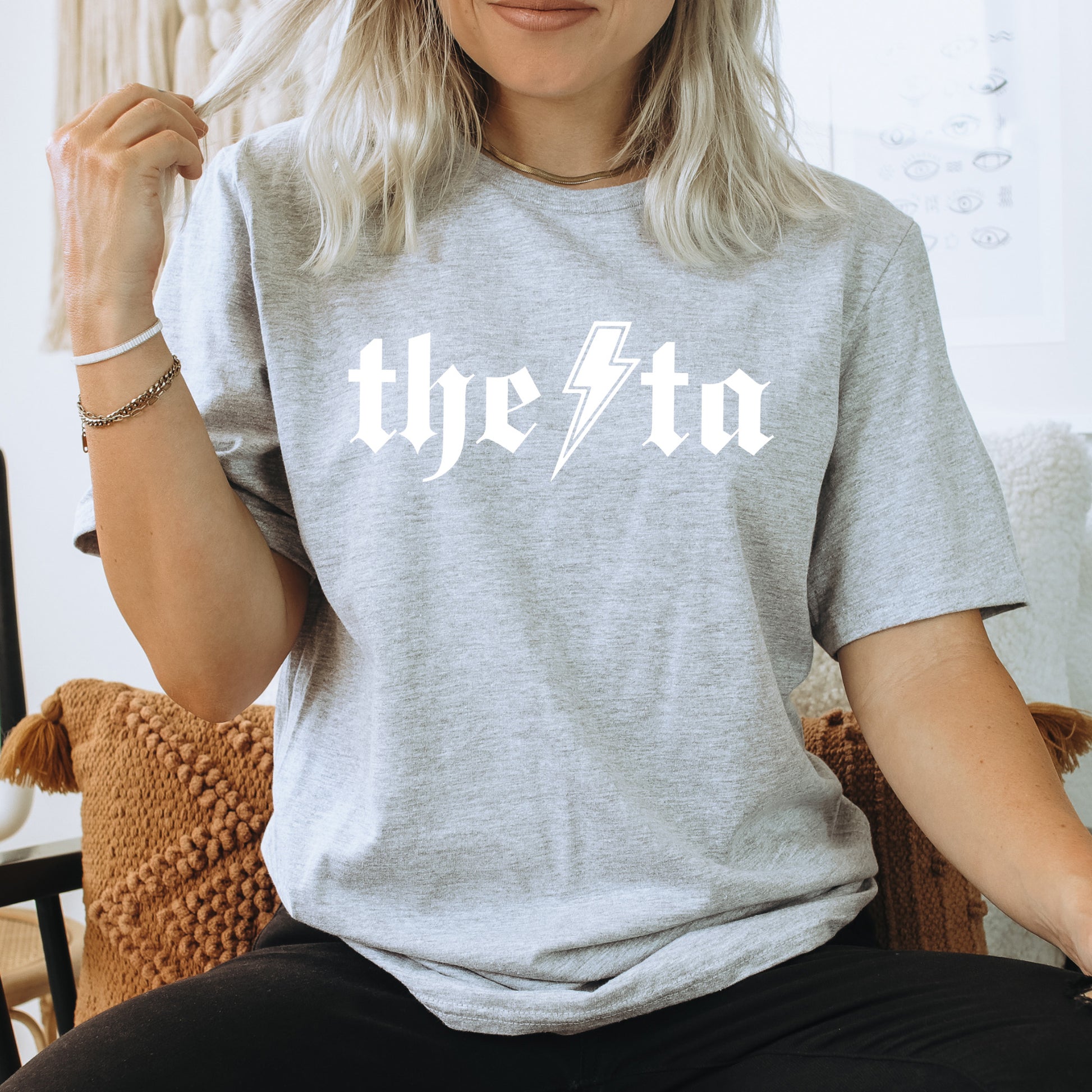 a woman sitting on a chair wearing a grey t - shirt with the word the