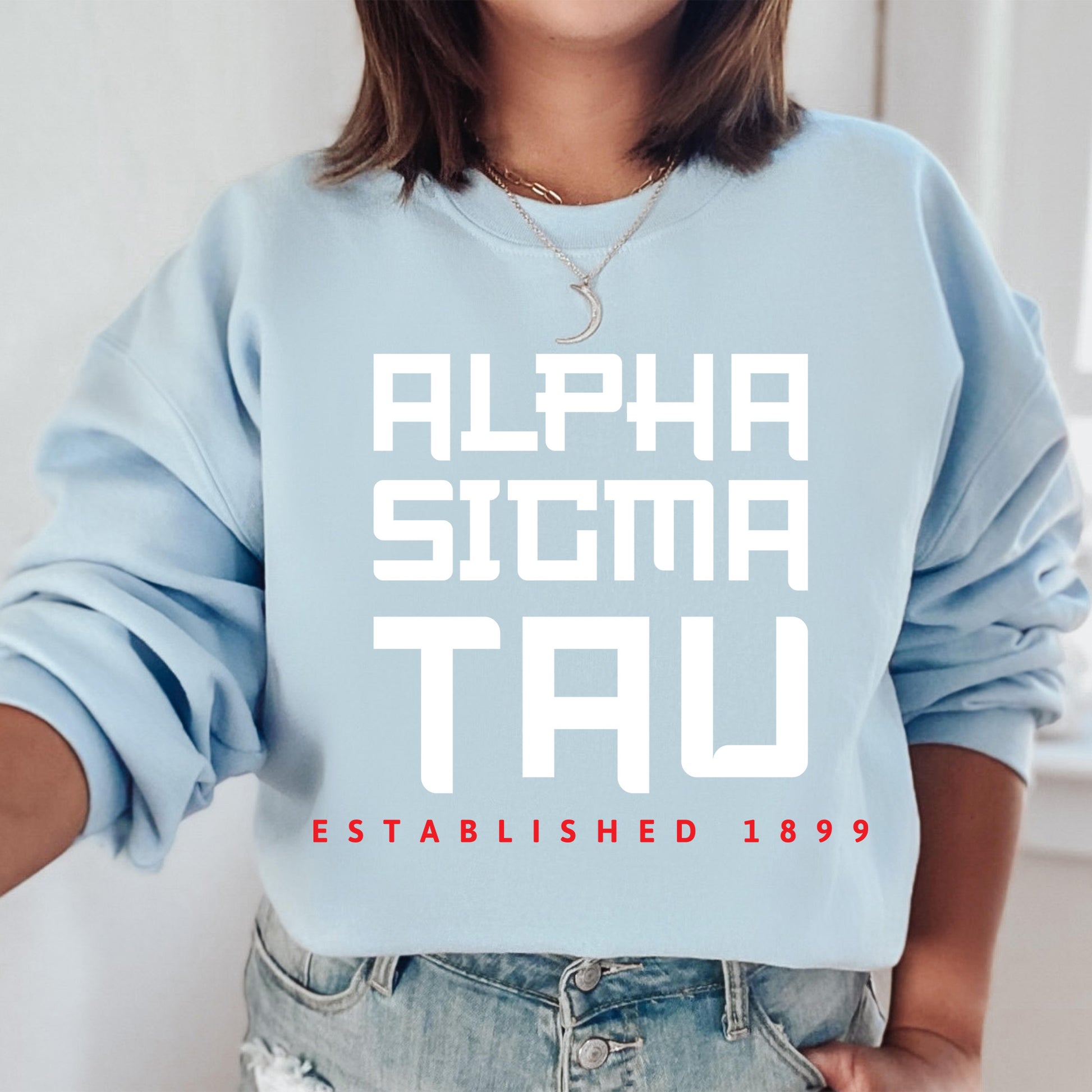 a woman wearing a blue sweatshirt with the words alpha sigma tau established