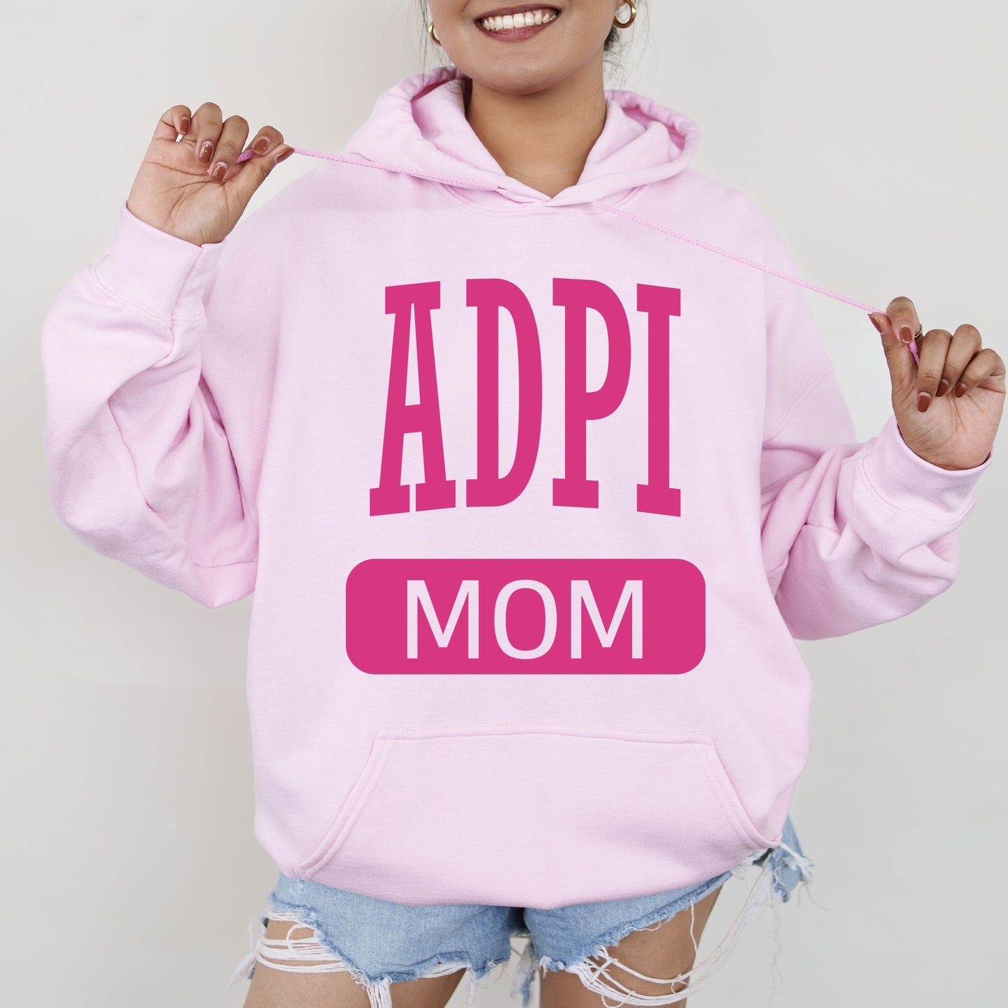 a woman wearing a pink hoodie that says appi mom