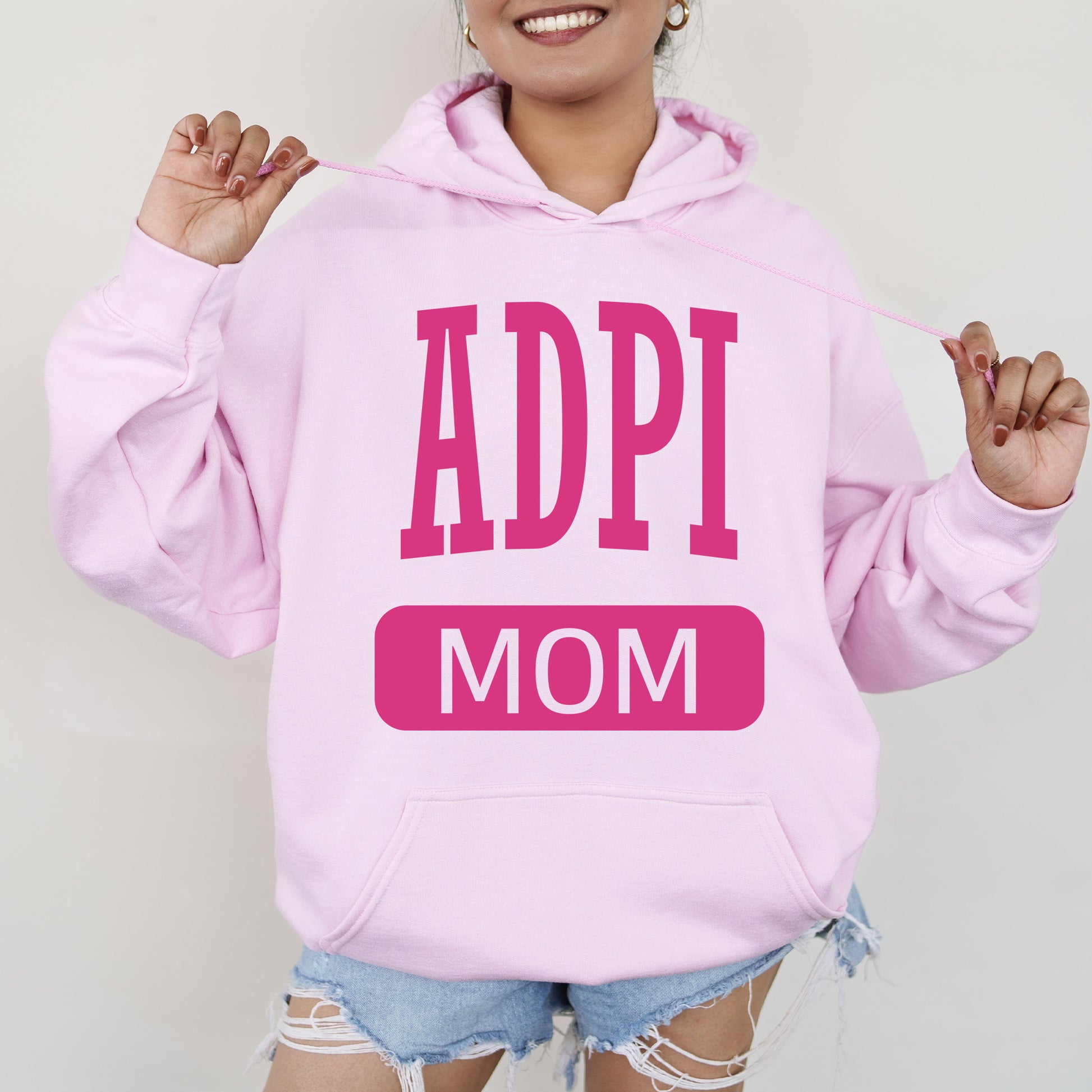 a woman wearing a pink hoodie that says appi mom