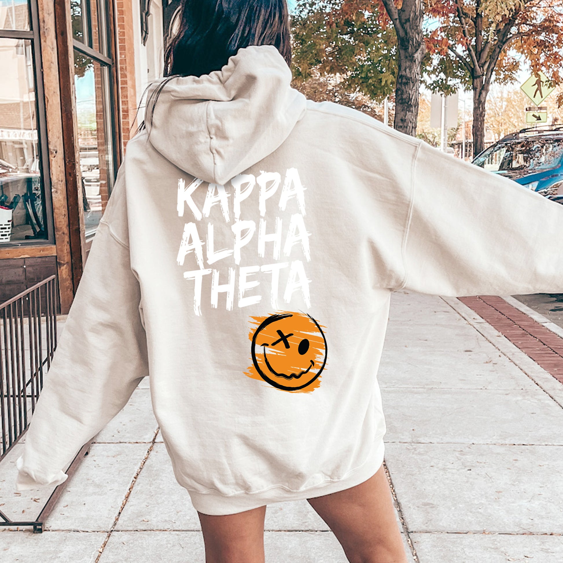 a woman walking down a sidewalk wearing a white hoodie
