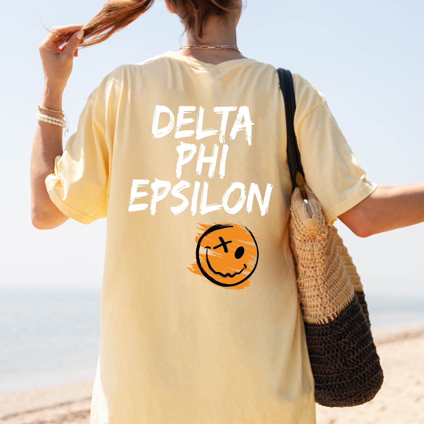 a woman walking on the beach with a smile on her shirt