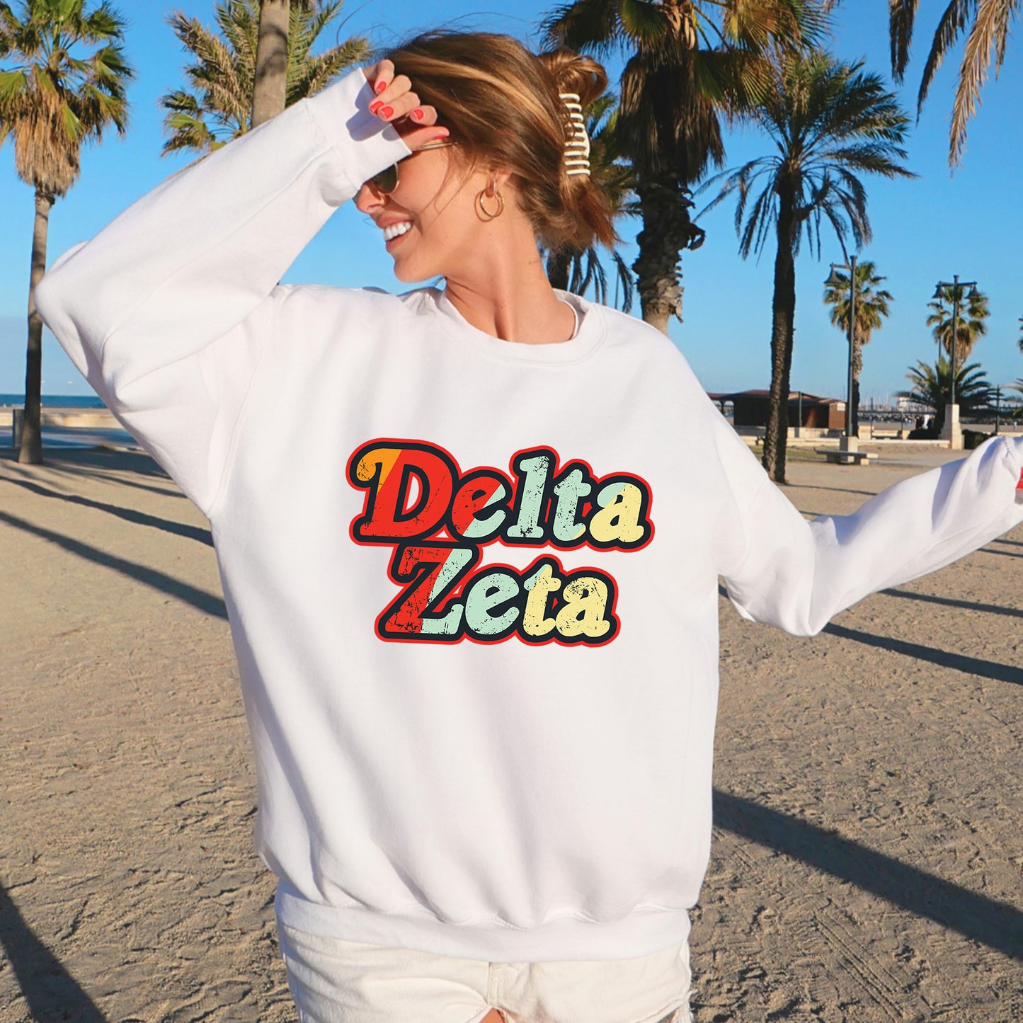 a woman standing on a beach wearing a white sweatshirt