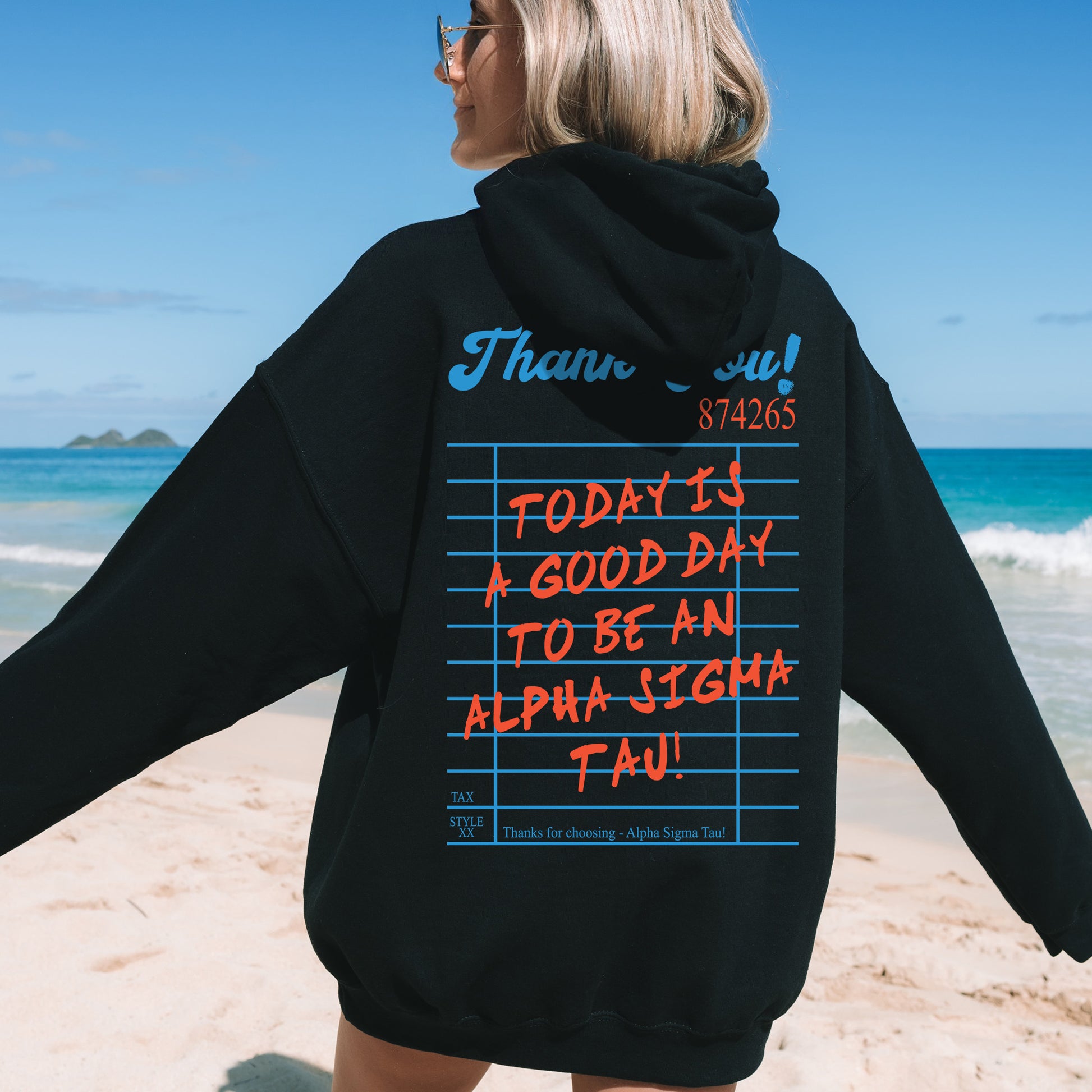 a woman standing on a beach wearing a black hoodie