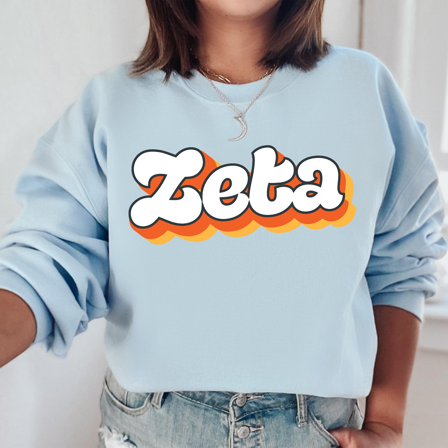 a woman wearing a blue sweatshirt with the word zeta printed on it