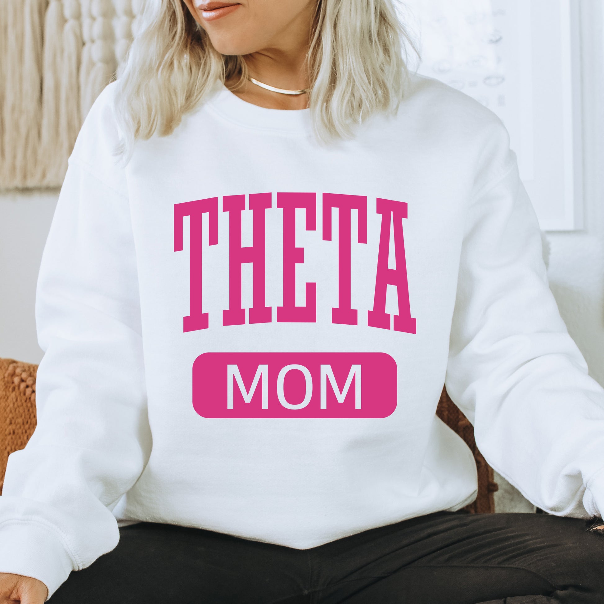 a woman sitting on a chair wearing a sweatshirt that says,'theta mom