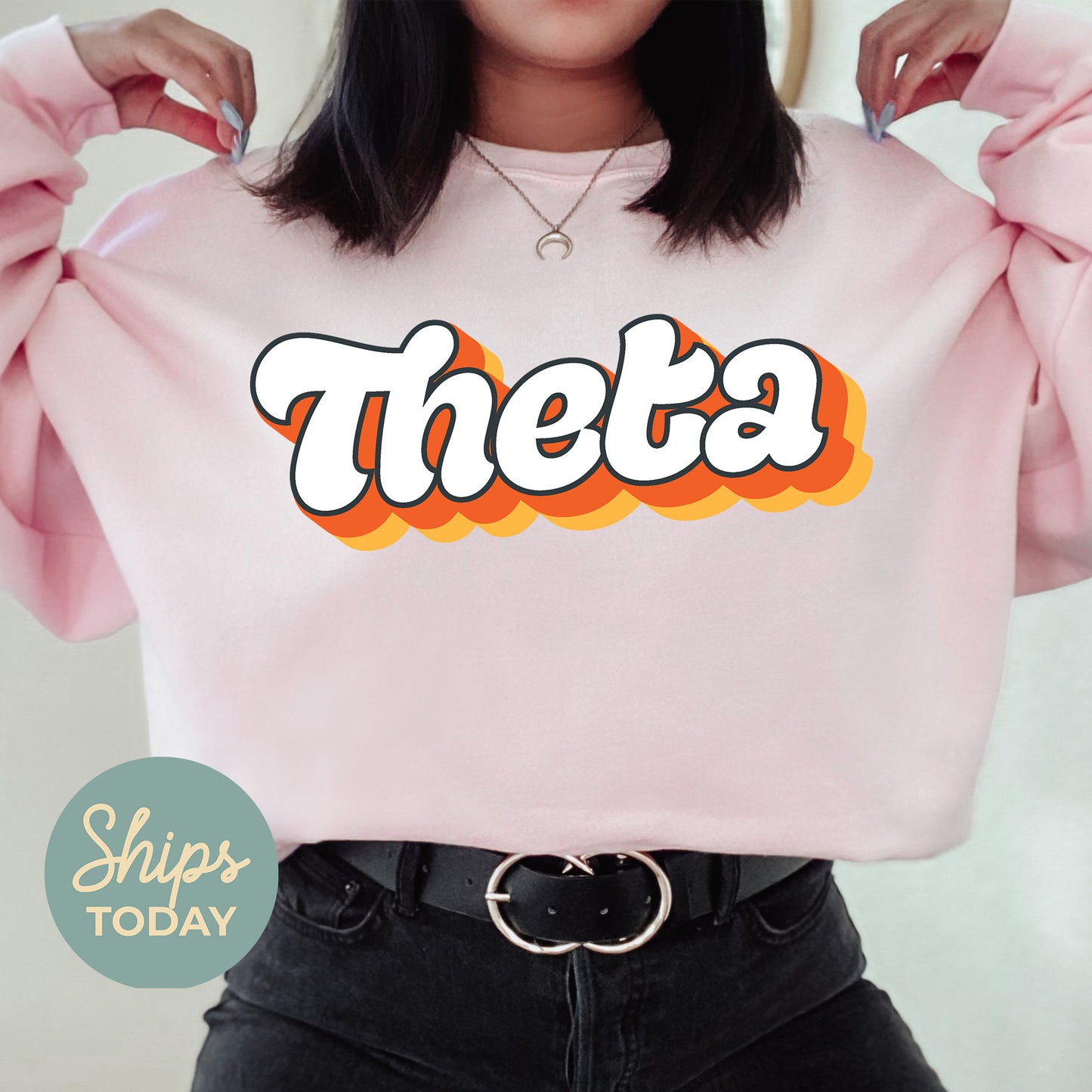 a woman wearing a pink sweatshirt with the word theeta on it