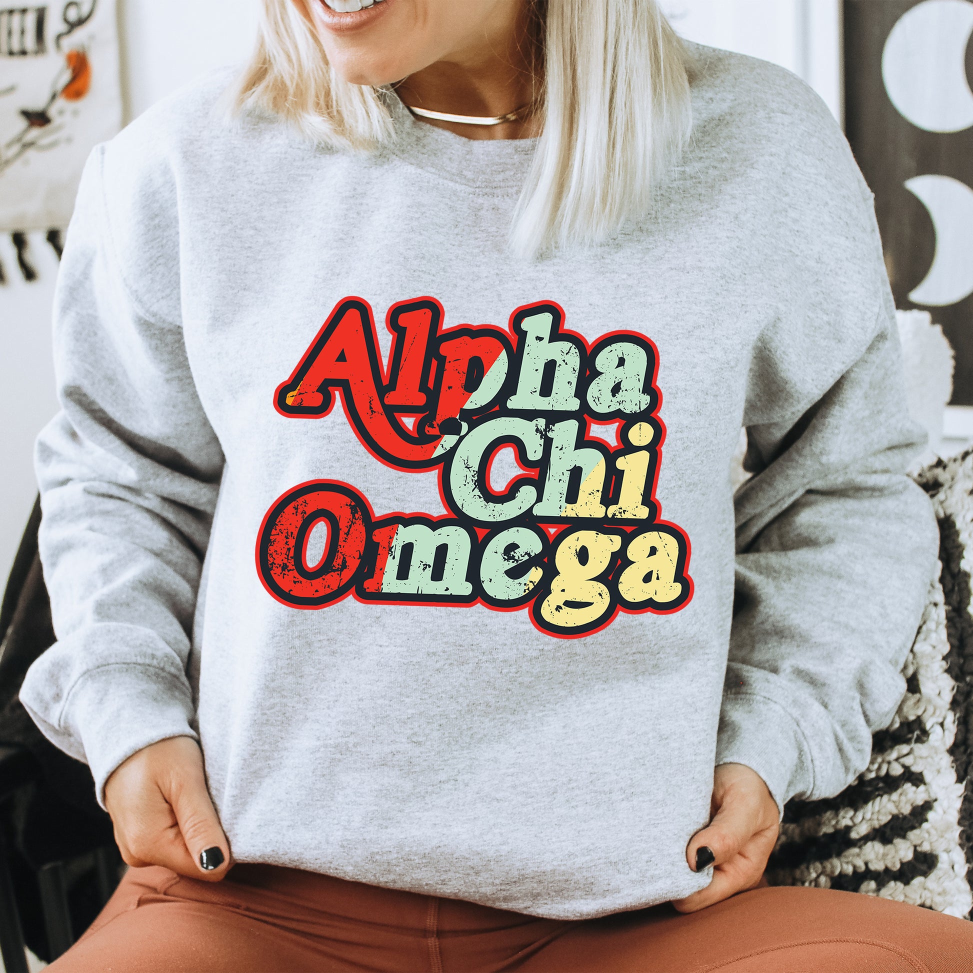 a woman sitting on a chair wearing a sweatshirt with the word'apha chi