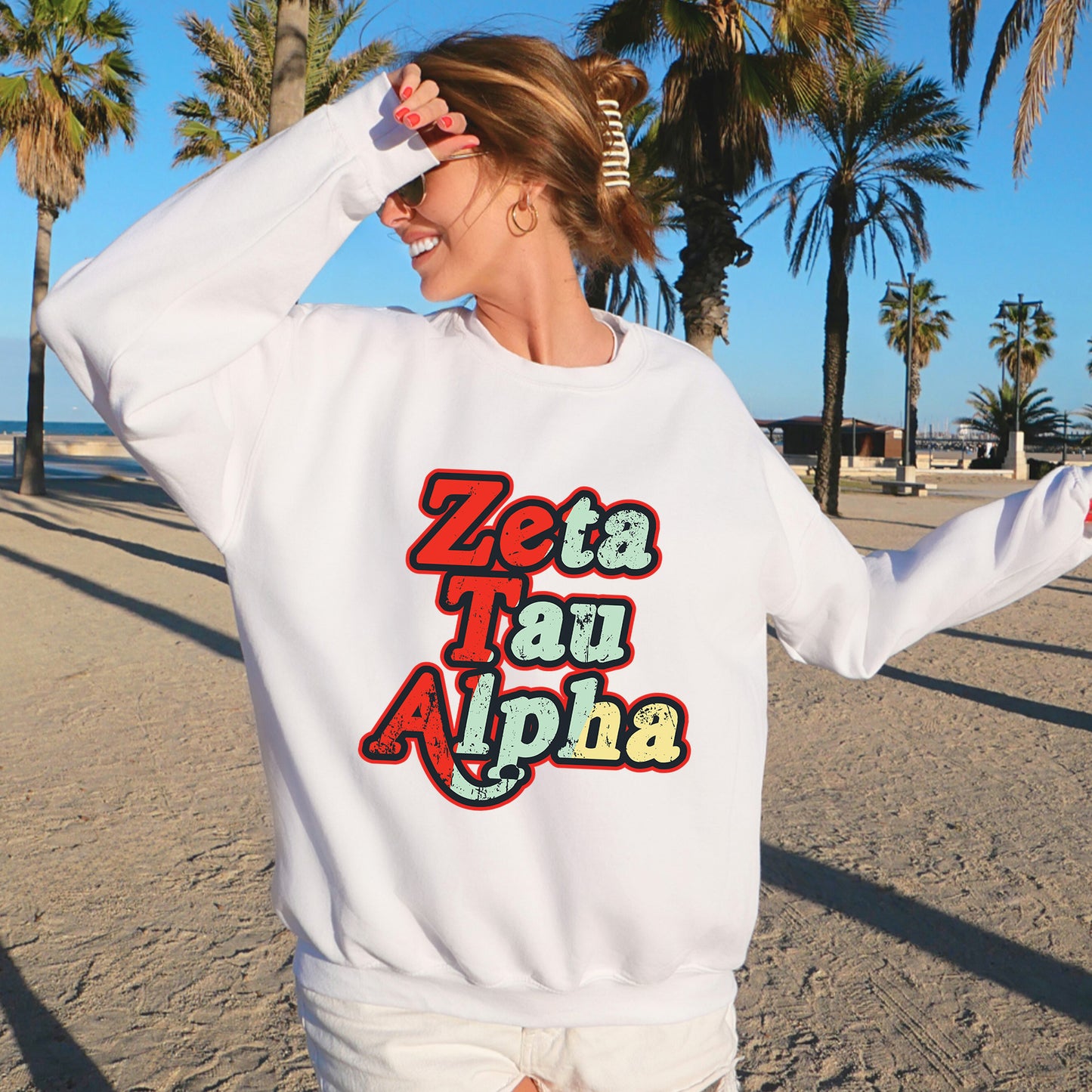 a woman standing on a beach wearing a white sweatshirt
