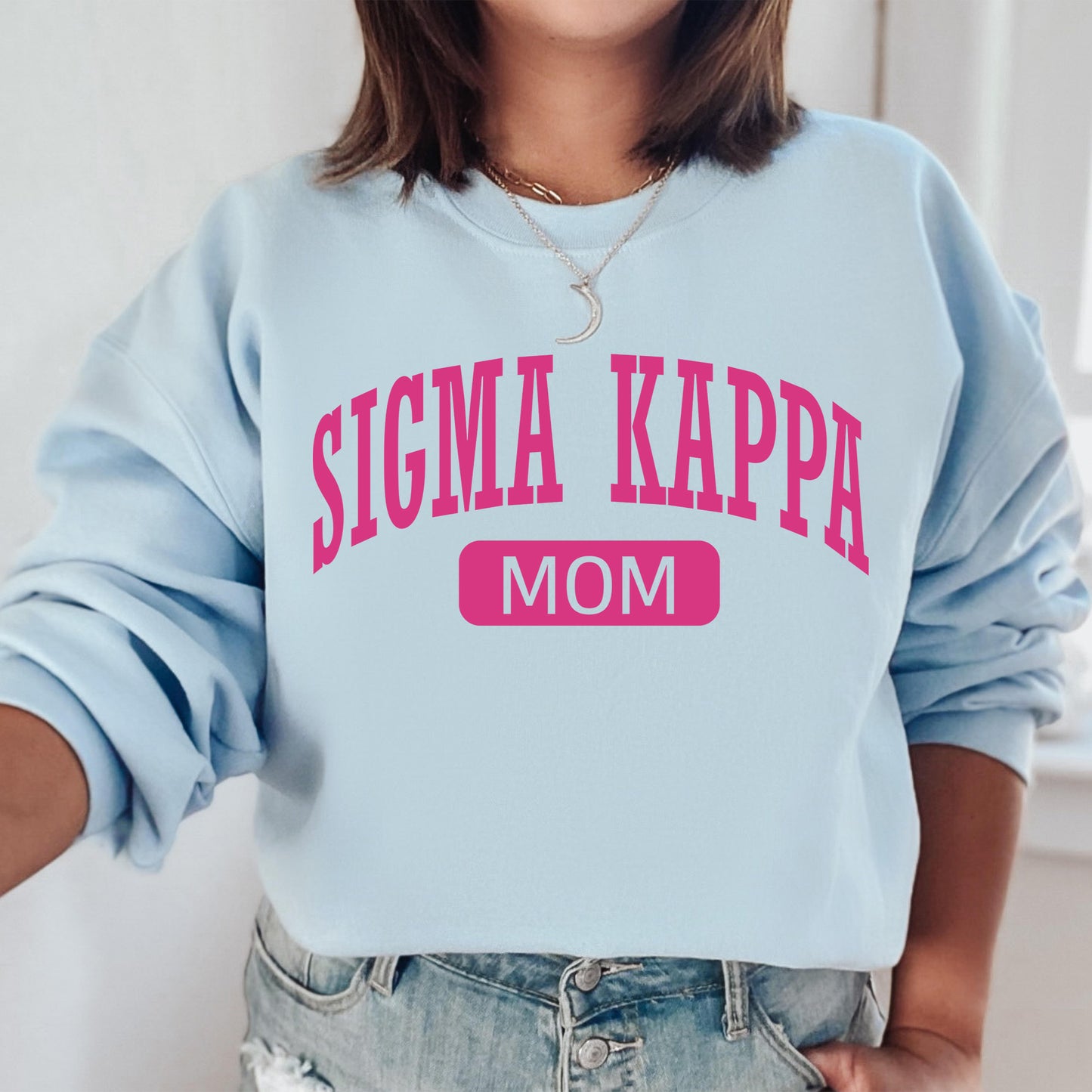 a woman wearing a light blue sweatshirt with pink lettering