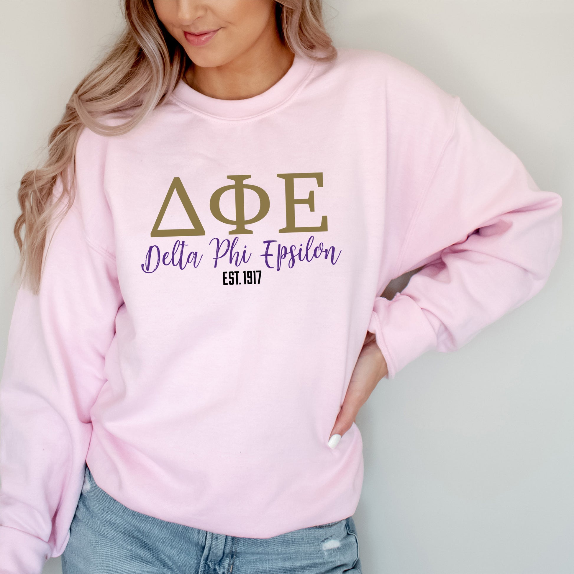 a woman wearing a pink sweatshirt with greek letters