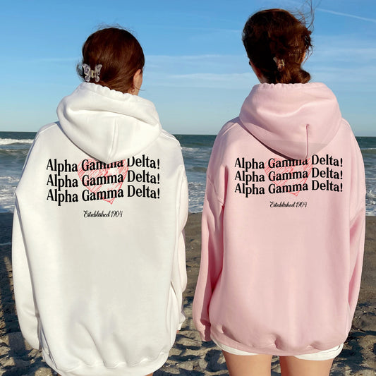 two women wearing pink and white hoodies on the beach