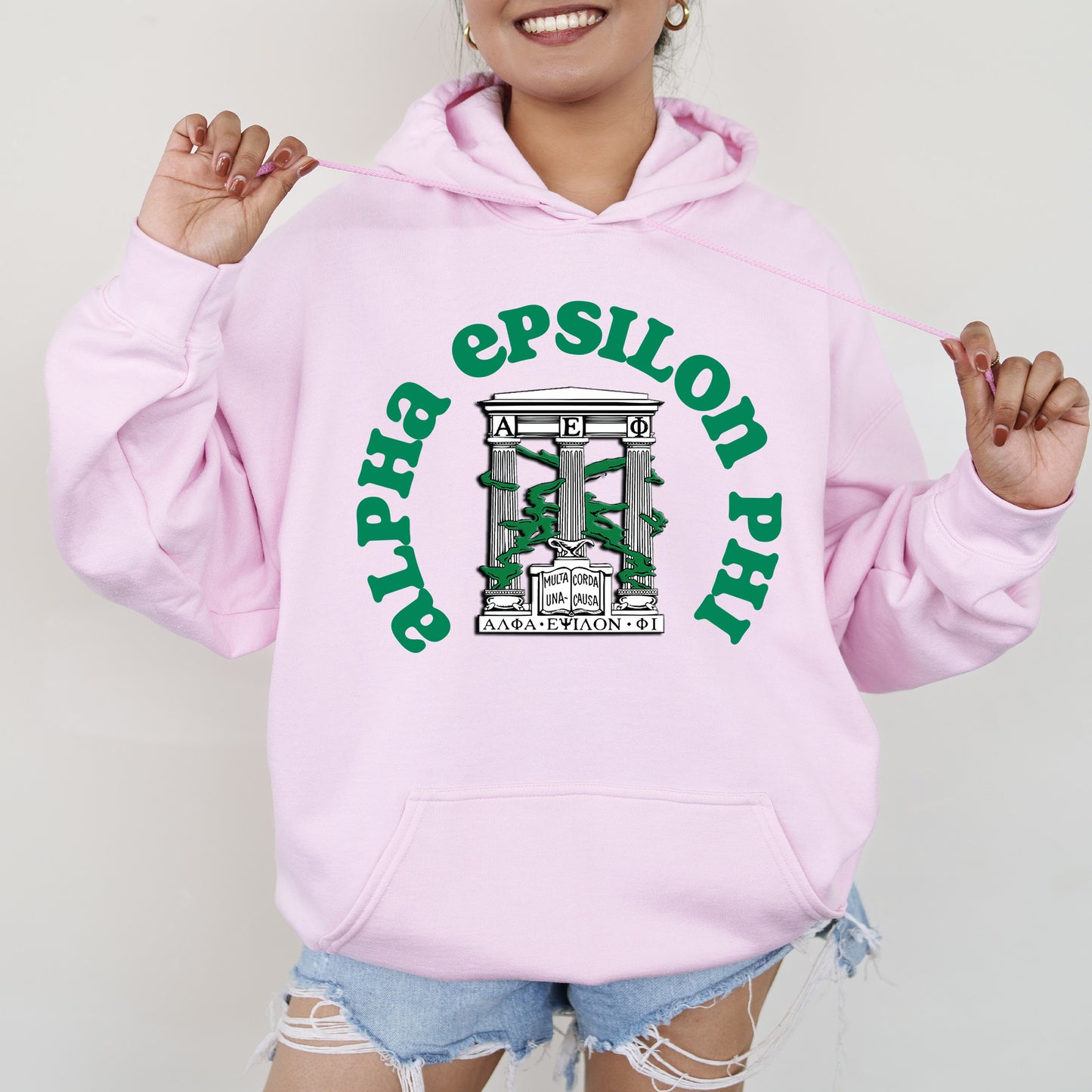 a woman wearing a pink sweatshirt and ripped shorts
