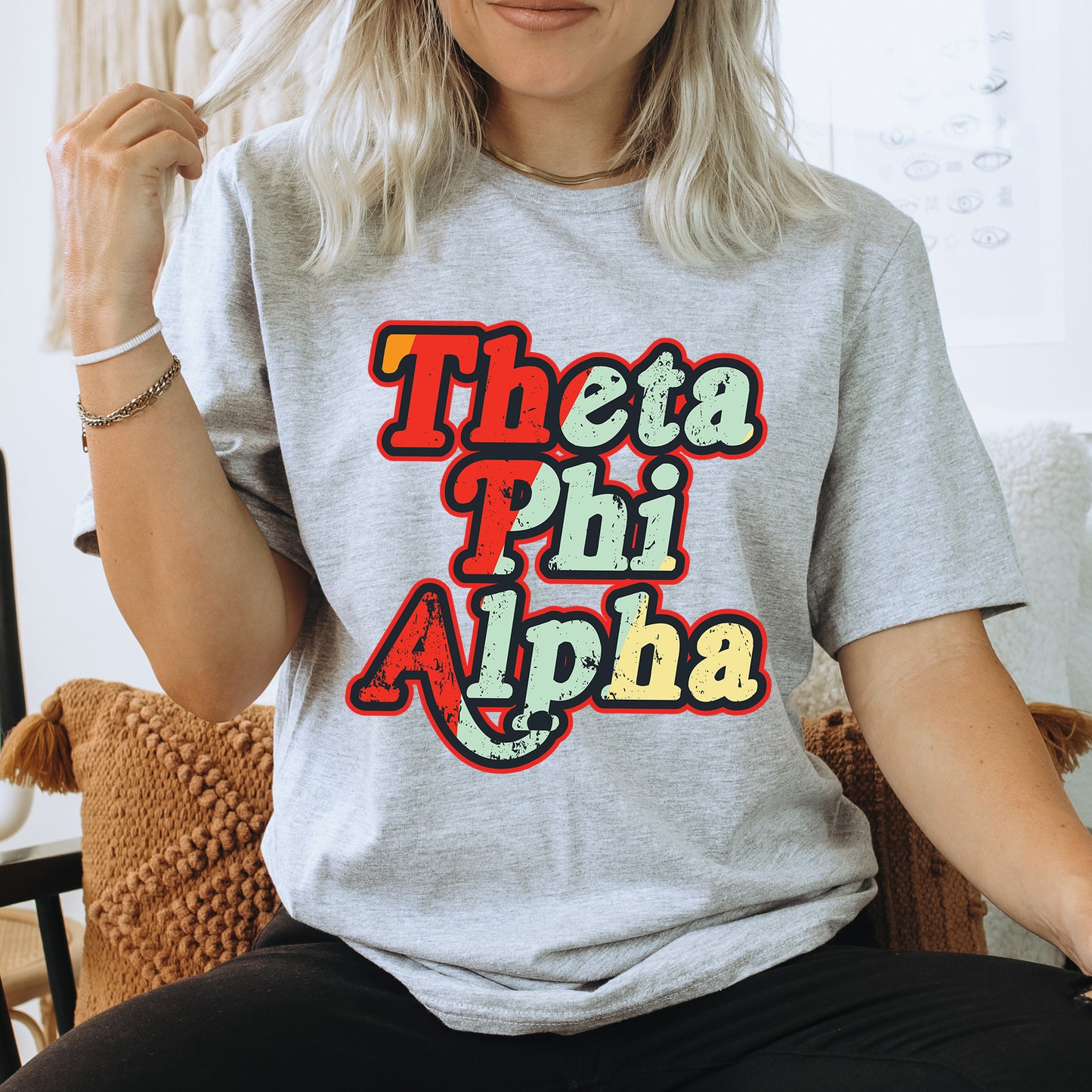 a woman sitting on a chair wearing a t - shirt that says thea phi