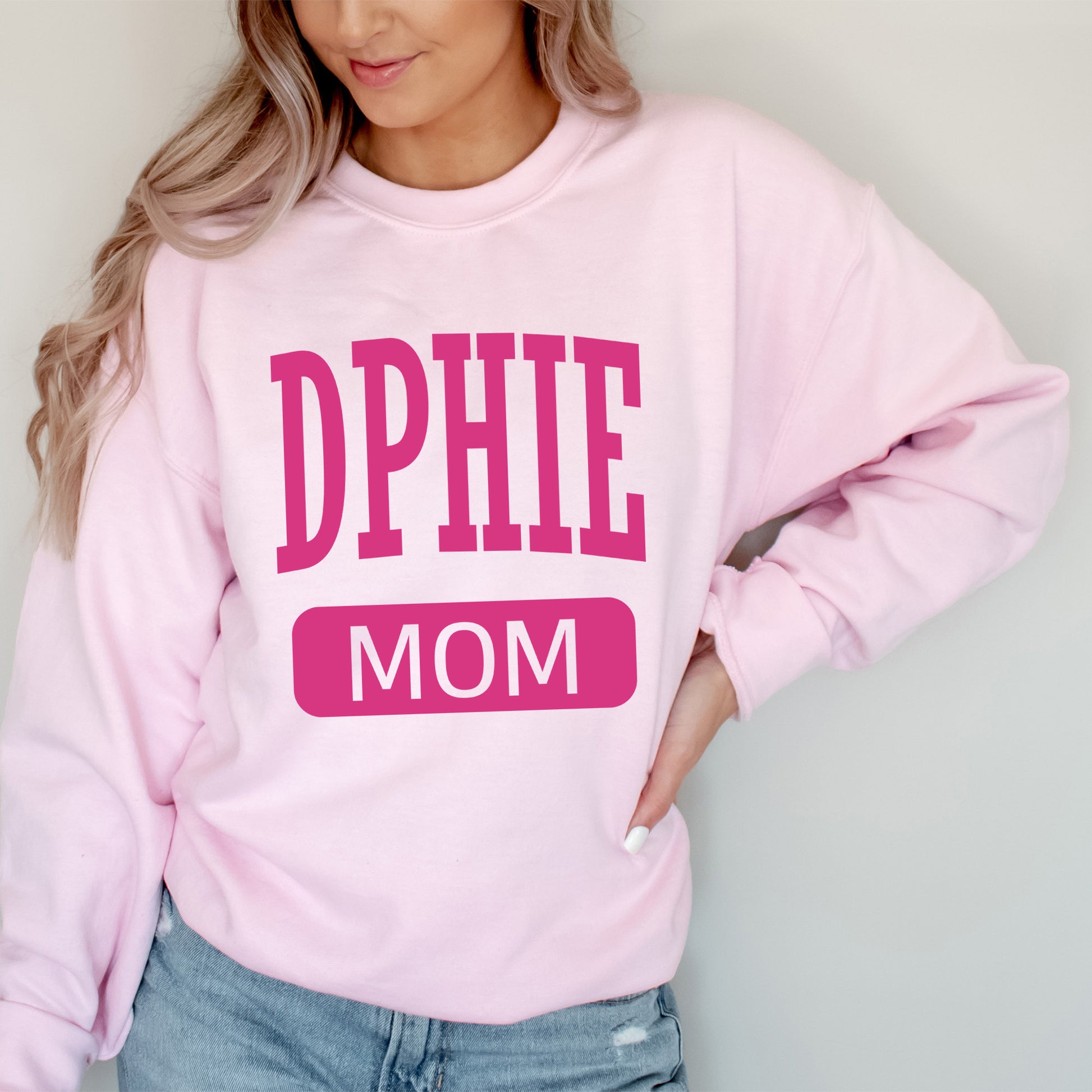 a woman wearing a pink sweatshirt with the words dppie mom on it