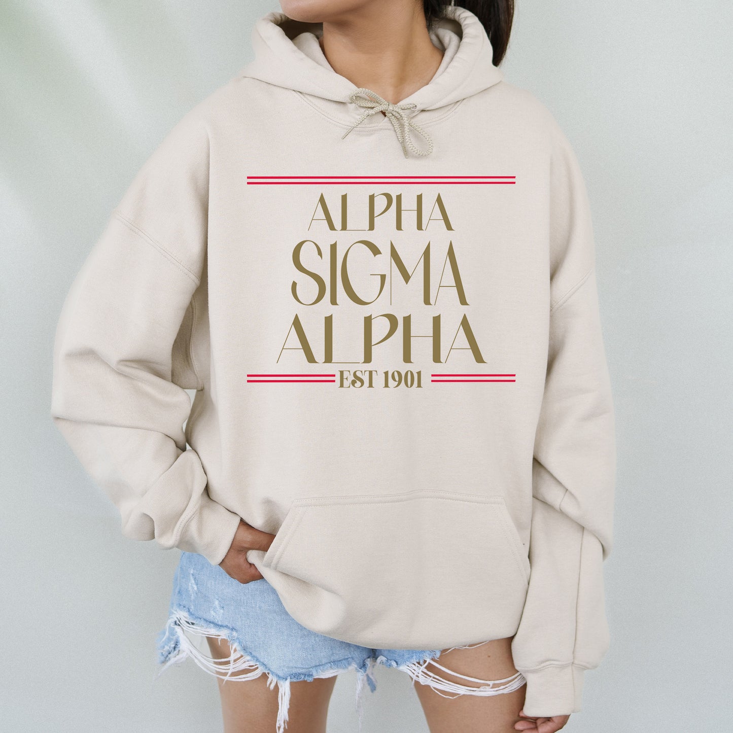 a woman wearing a white sweatshirt with the words, alpha, and a red stripe
