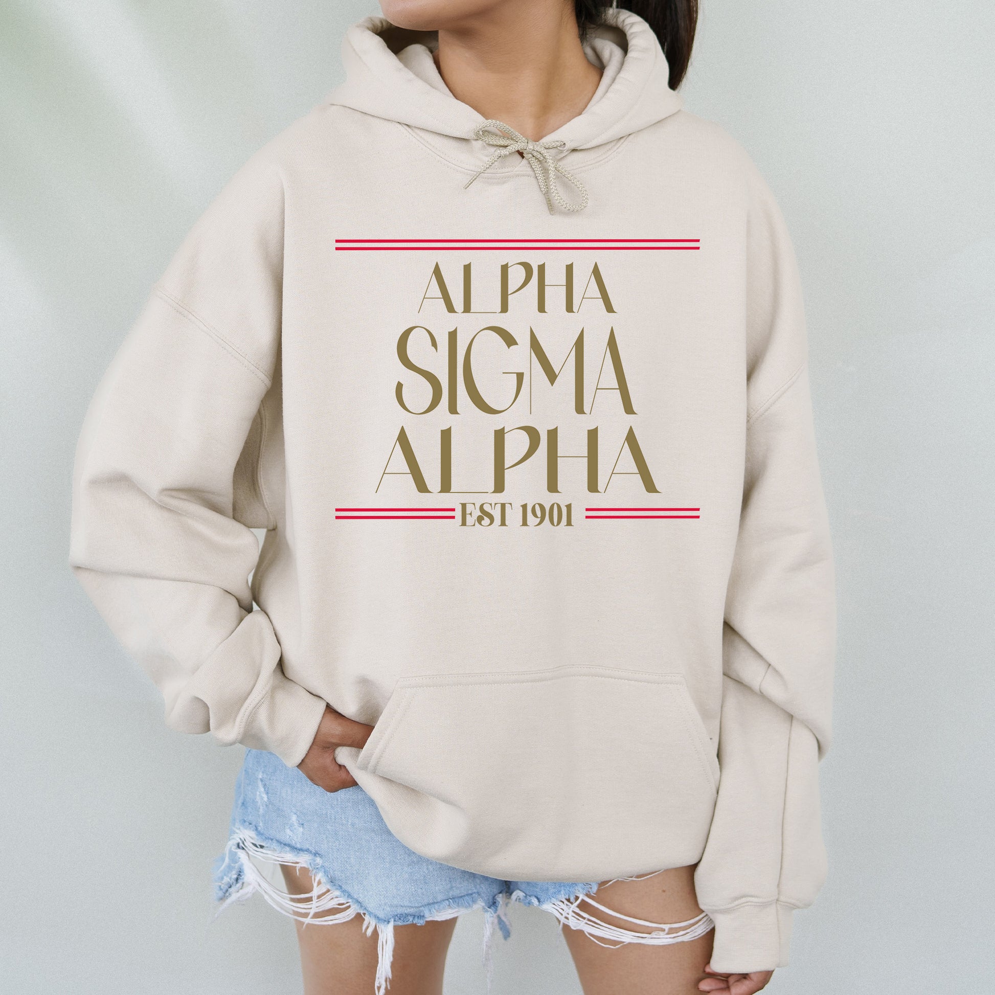 a woman wearing a white sweatshirt with the words, alpha, and a red stripe