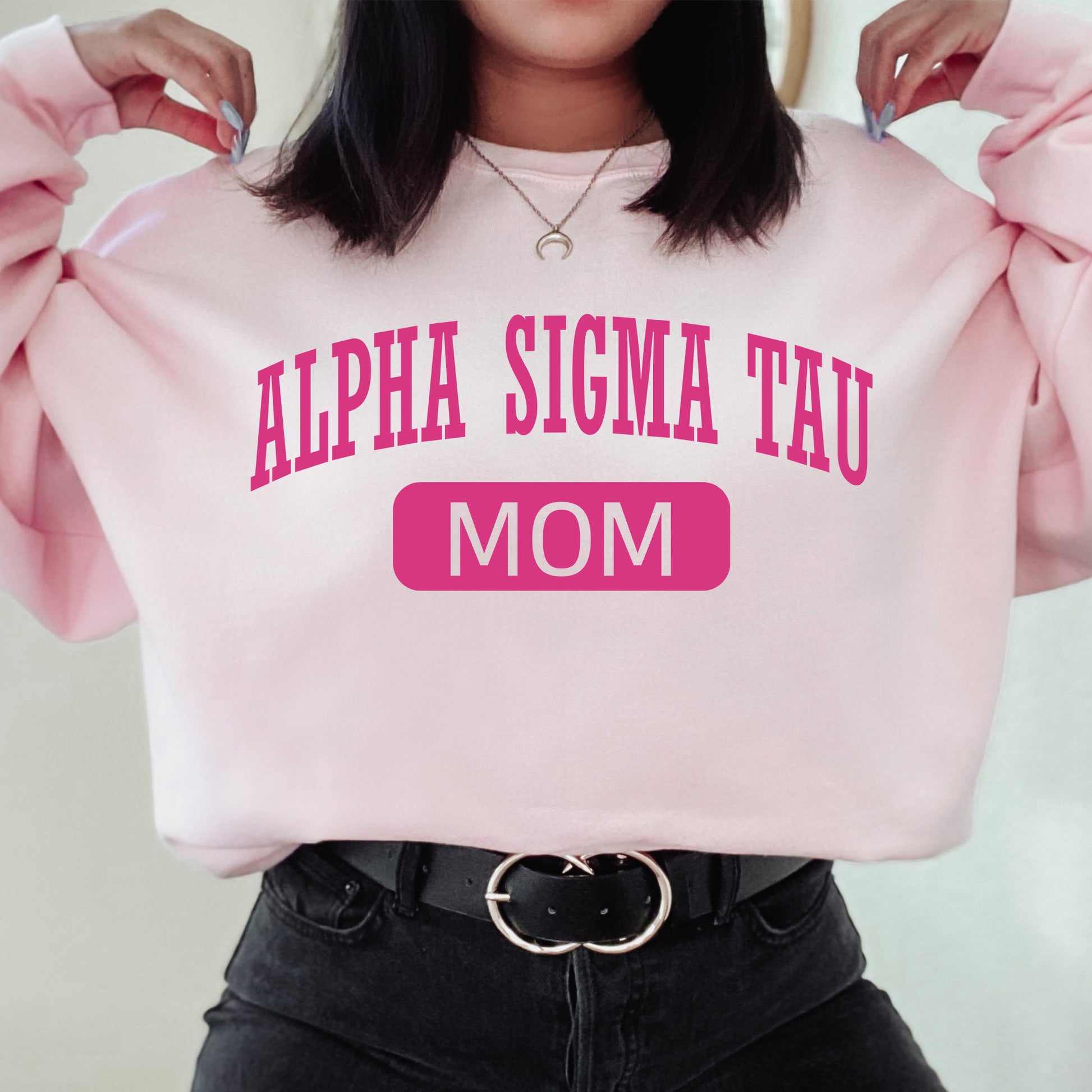 a woman wearing a pink sweatshirt with the words, alpha sigma tau