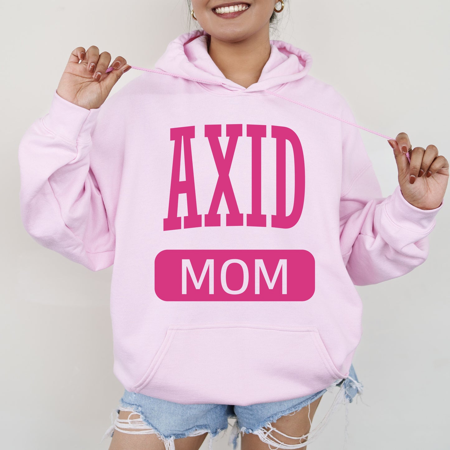 a woman wearing a pink hoodie that says axd mom
