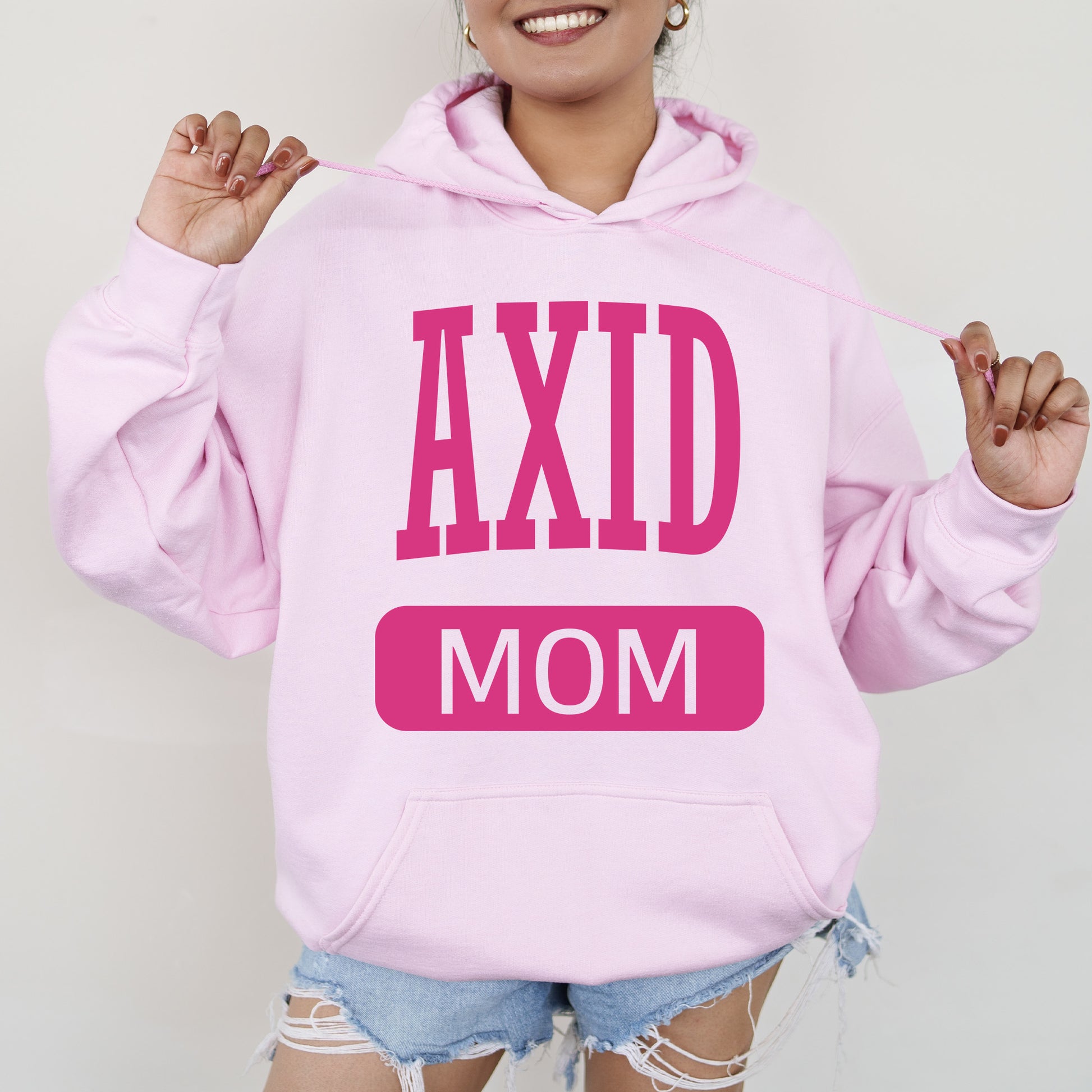 a woman wearing a pink hoodie that says axd mom