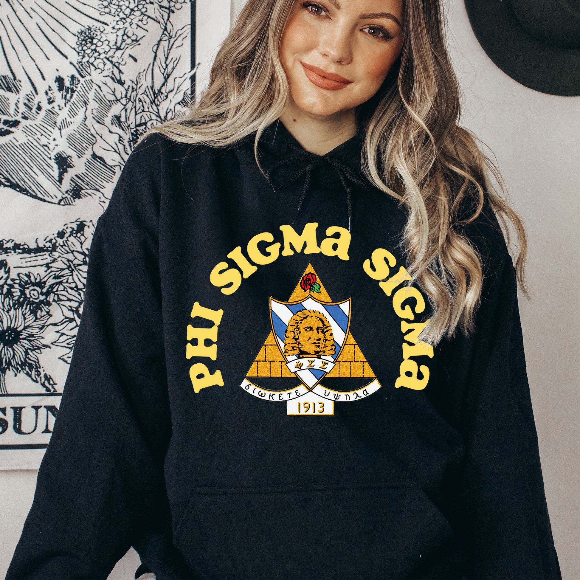 a woman wearing a black hoodie with the phi sigma sign on it