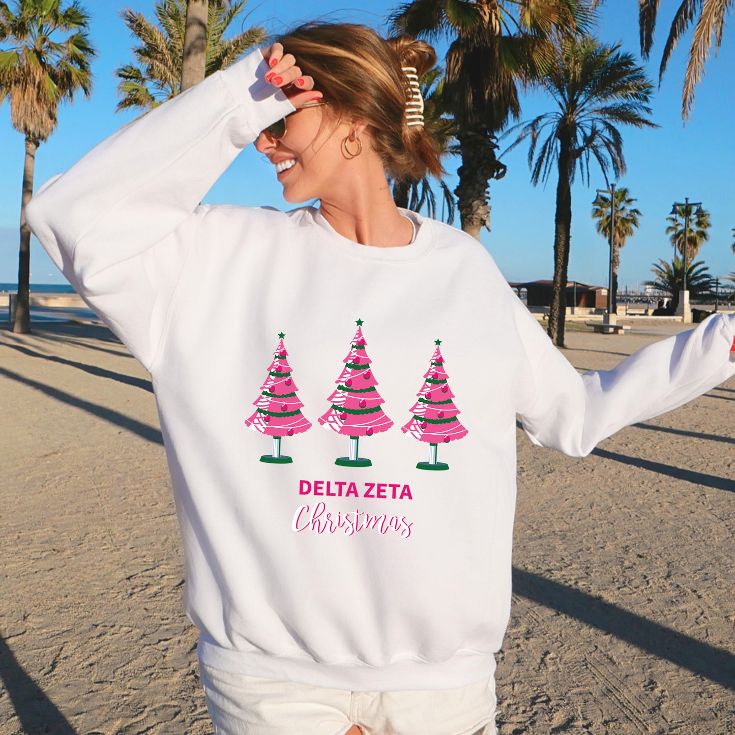 a woman wearing a white sweatshirt with pink trees on it