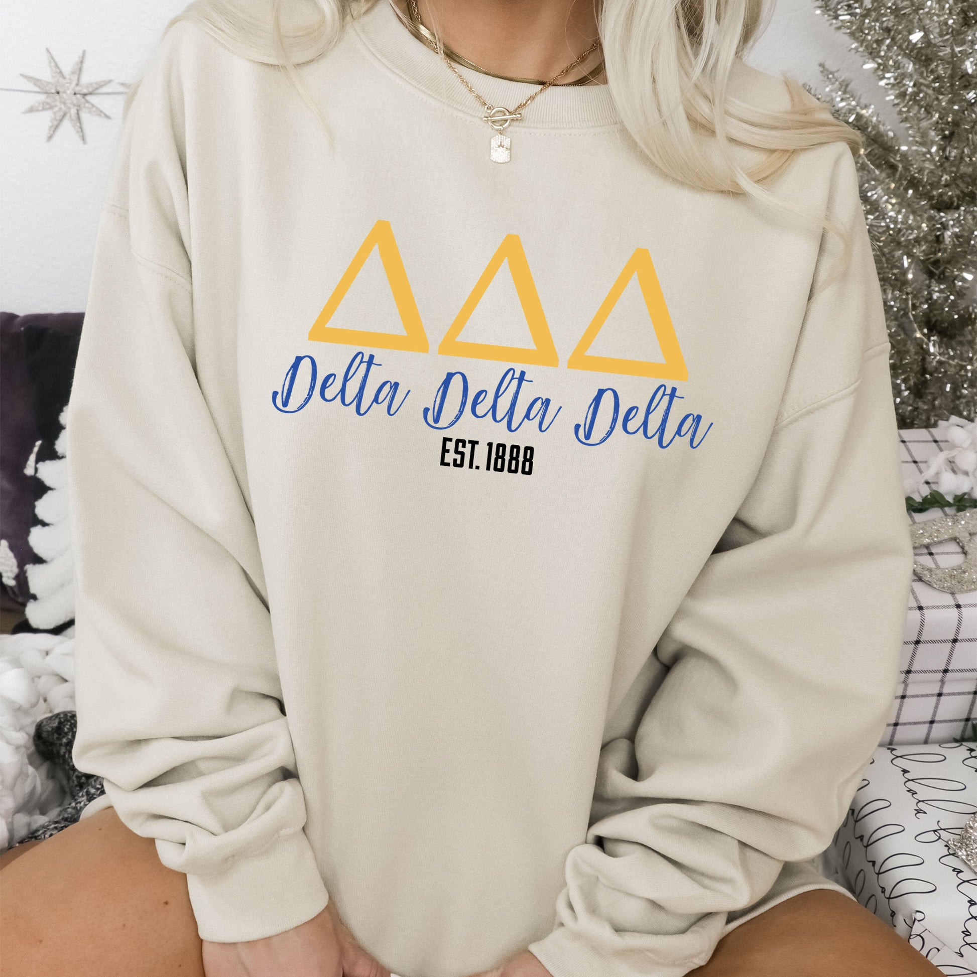 a woman sitting on a bed wearing a sweatshirt
