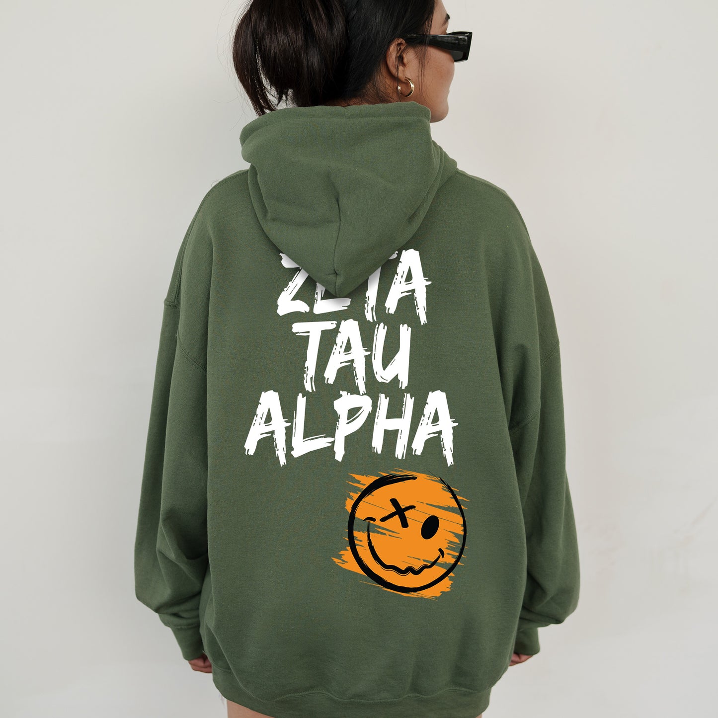 a woman wearing a green hoodie with a smiley face on it