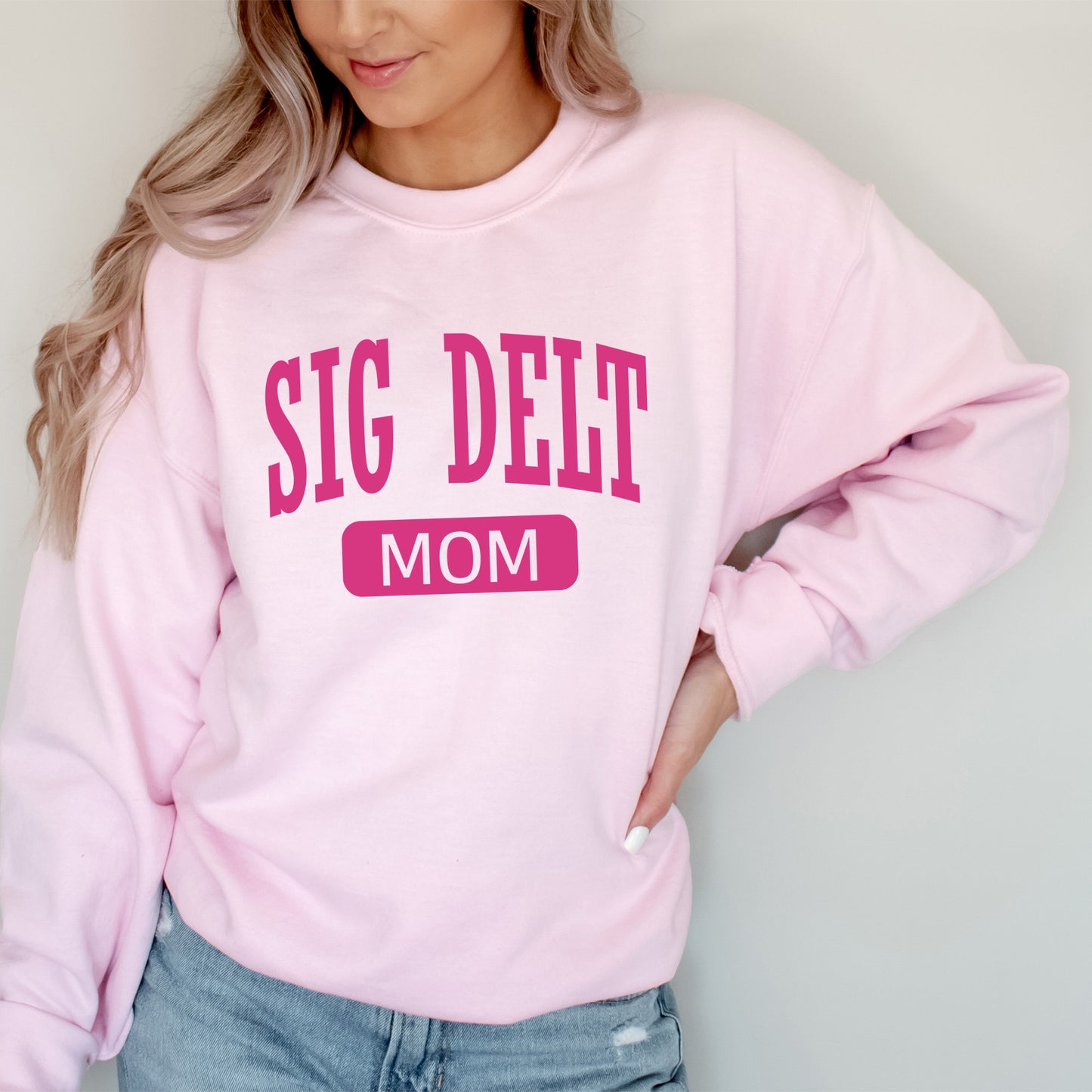 a woman wearing a pink sweatshirt that says sig delt mom