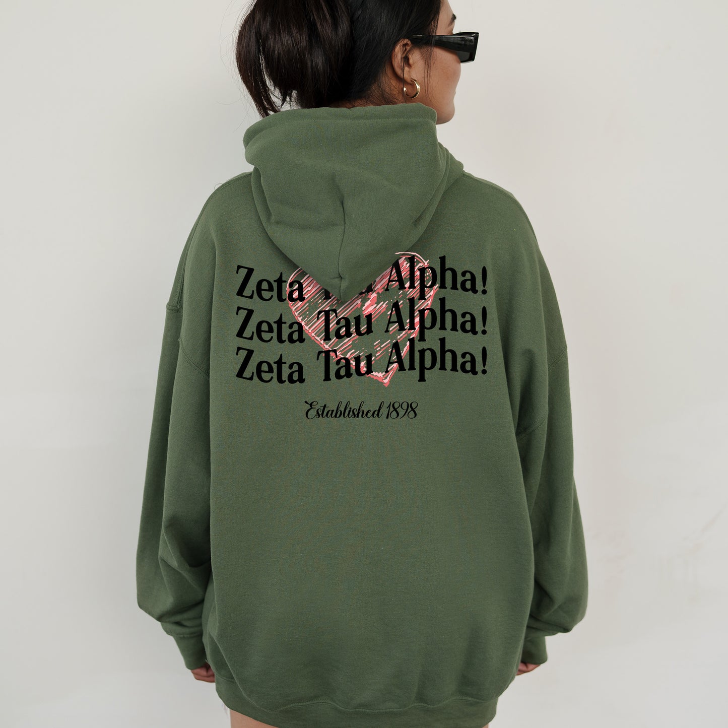 a woman wearing a green hoodie with a pink ribbon on it