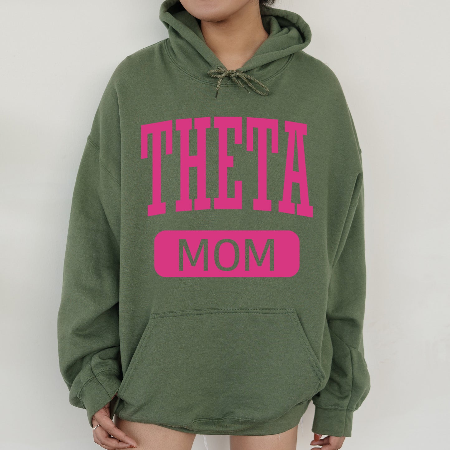 a woman wearing a green sweatshirt with pink letters on it