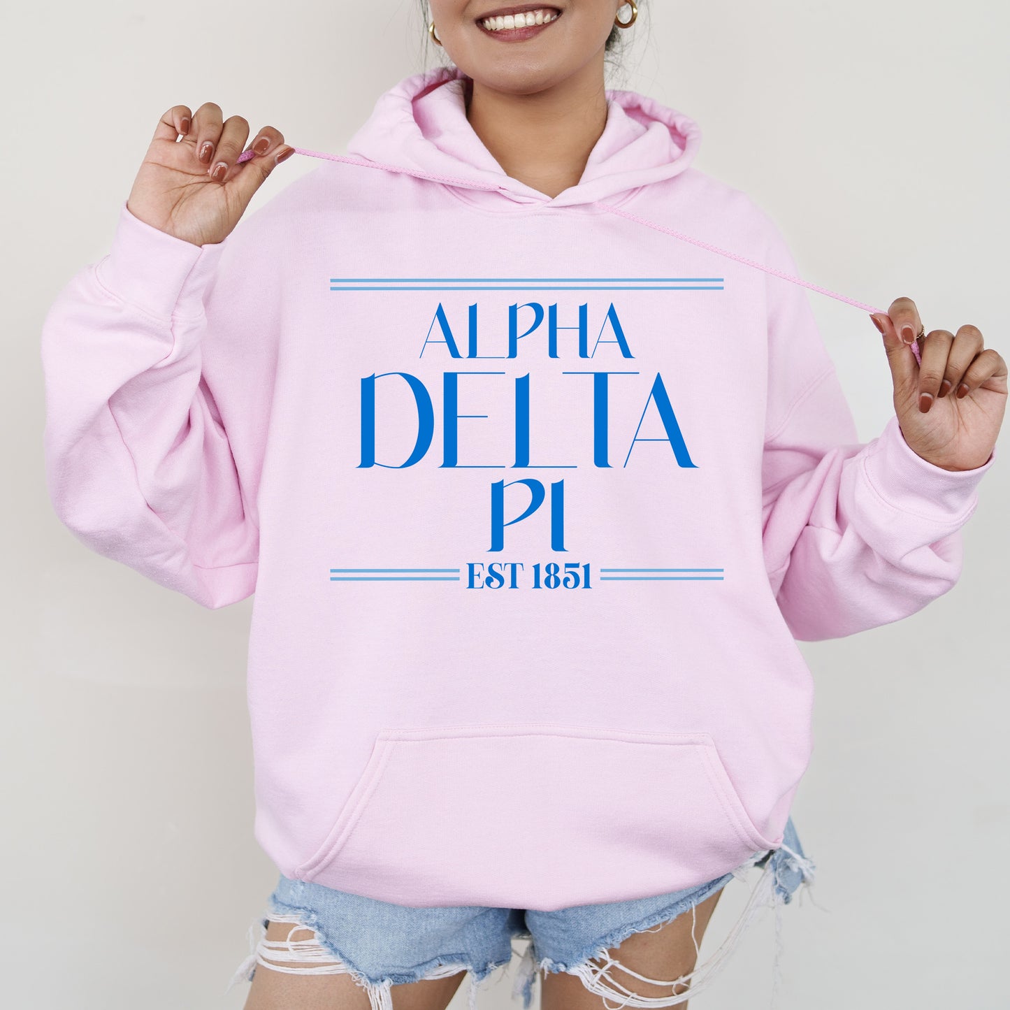 a woman wearing a pink hoodie with the word delta printed on it