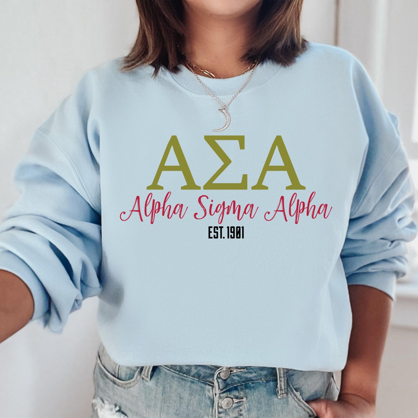 a woman wearing a light blue sweatshirt with the letters aza on it