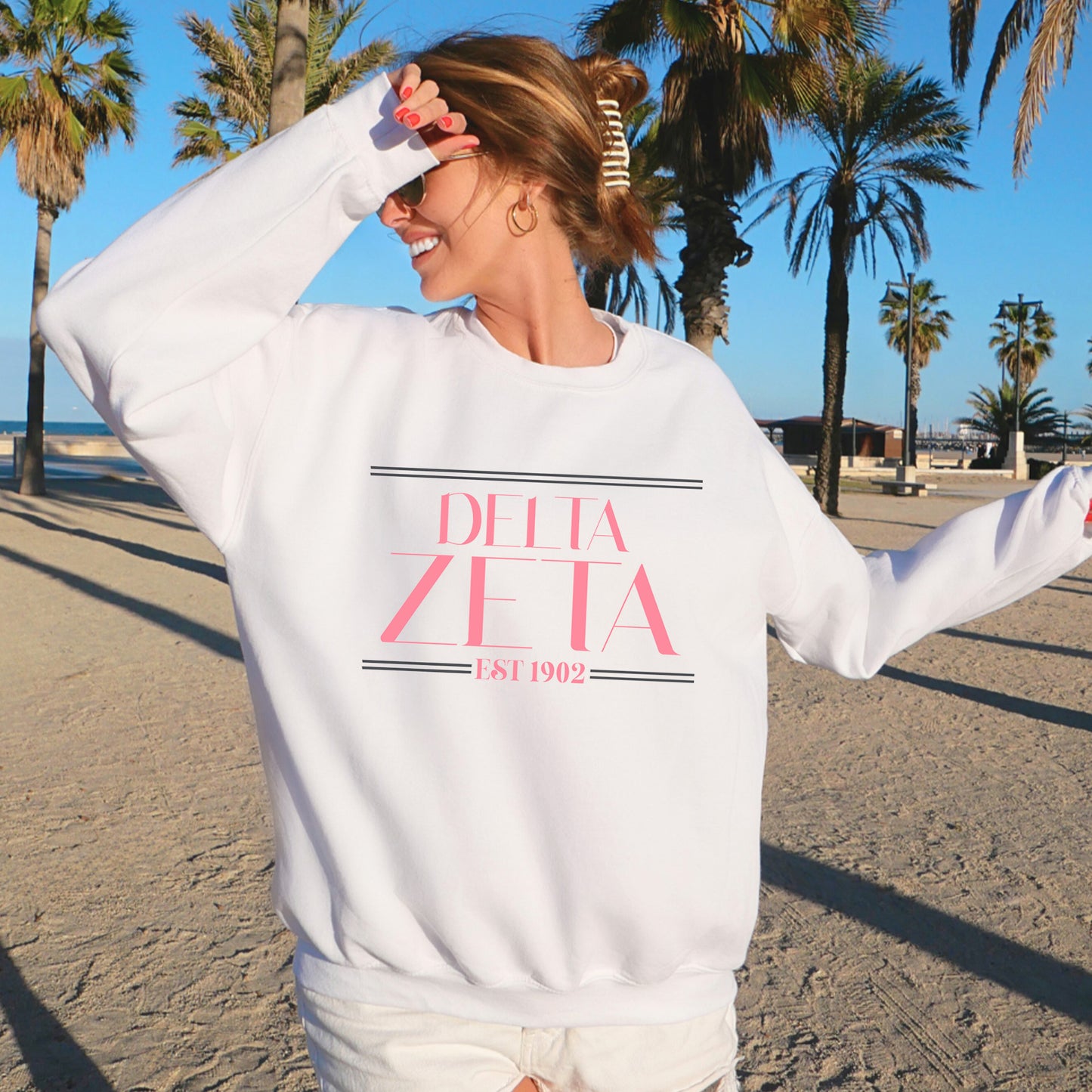a woman standing on a beach wearing a white sweatshirt