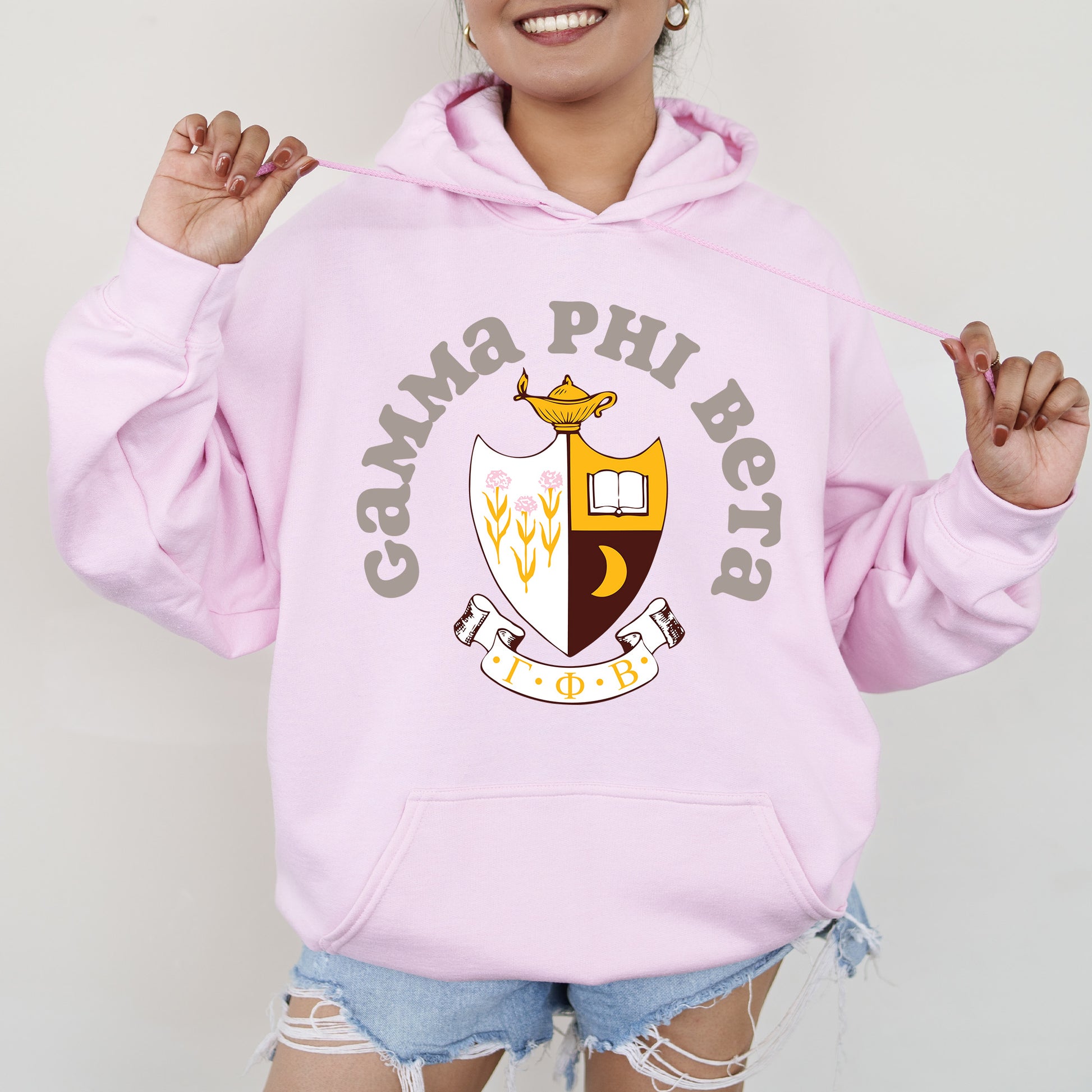a woman wearing a pink hoodie with a crest on it