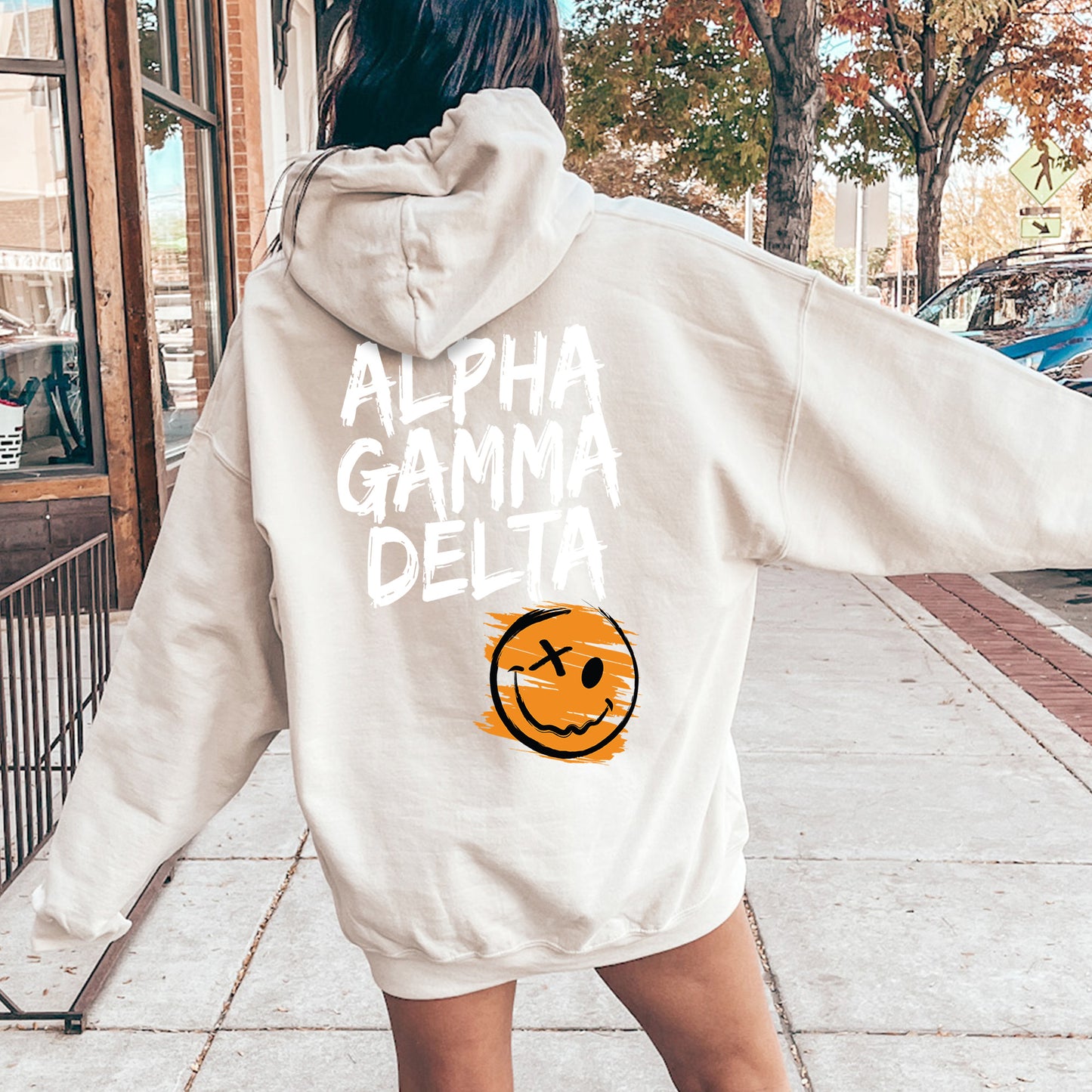 a woman walking down a sidewalk wearing a white hoodie