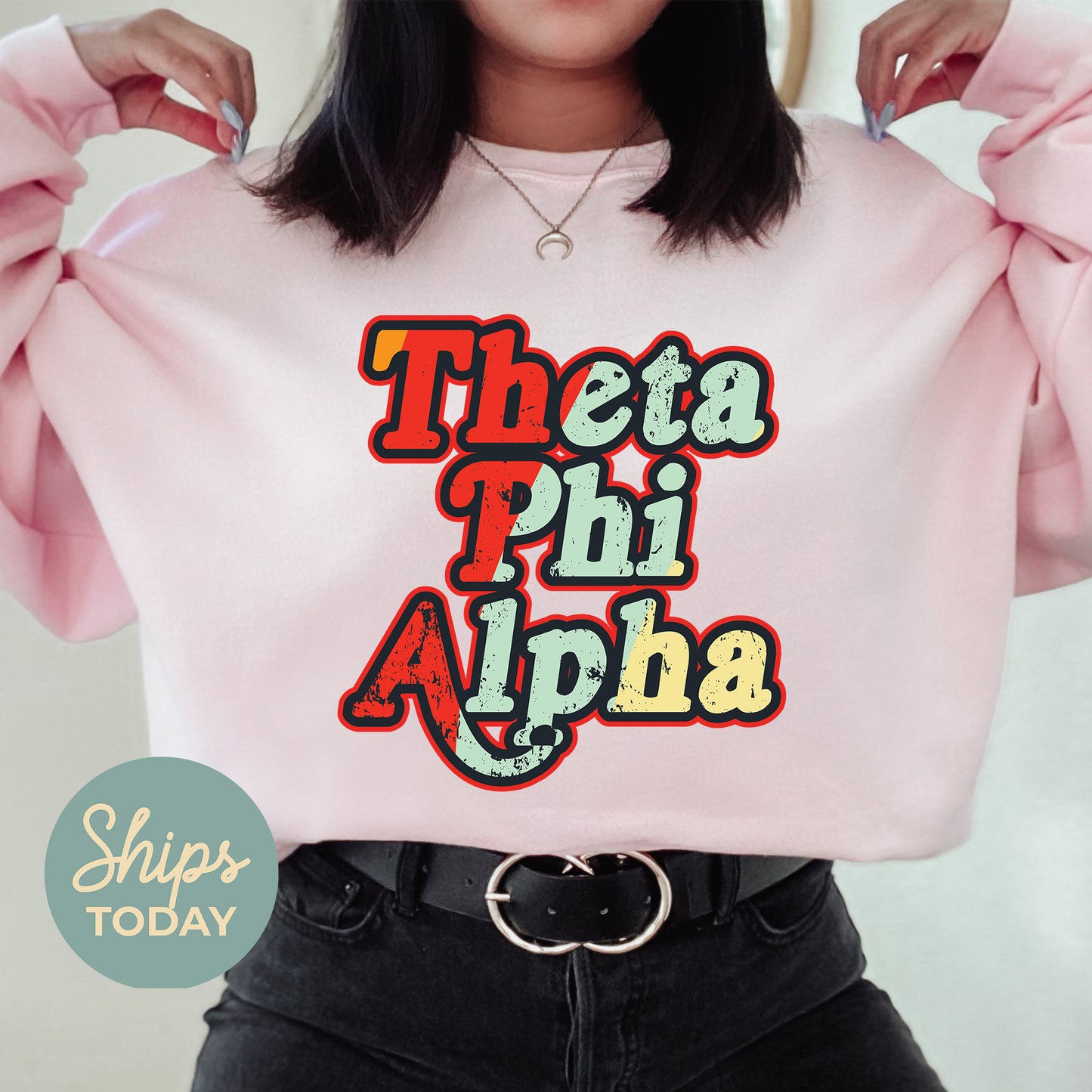 a woman wearing a pink sweatshirt with the words thea phi ah on it