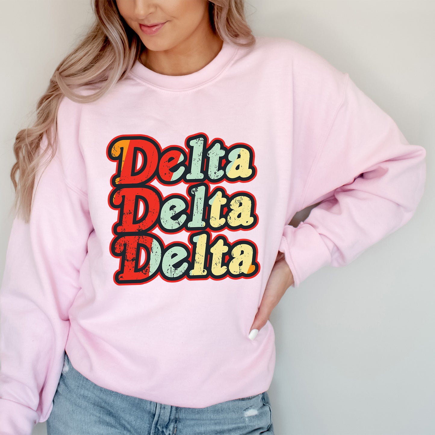 a woman wearing a pink sweatshirt that says delta delta