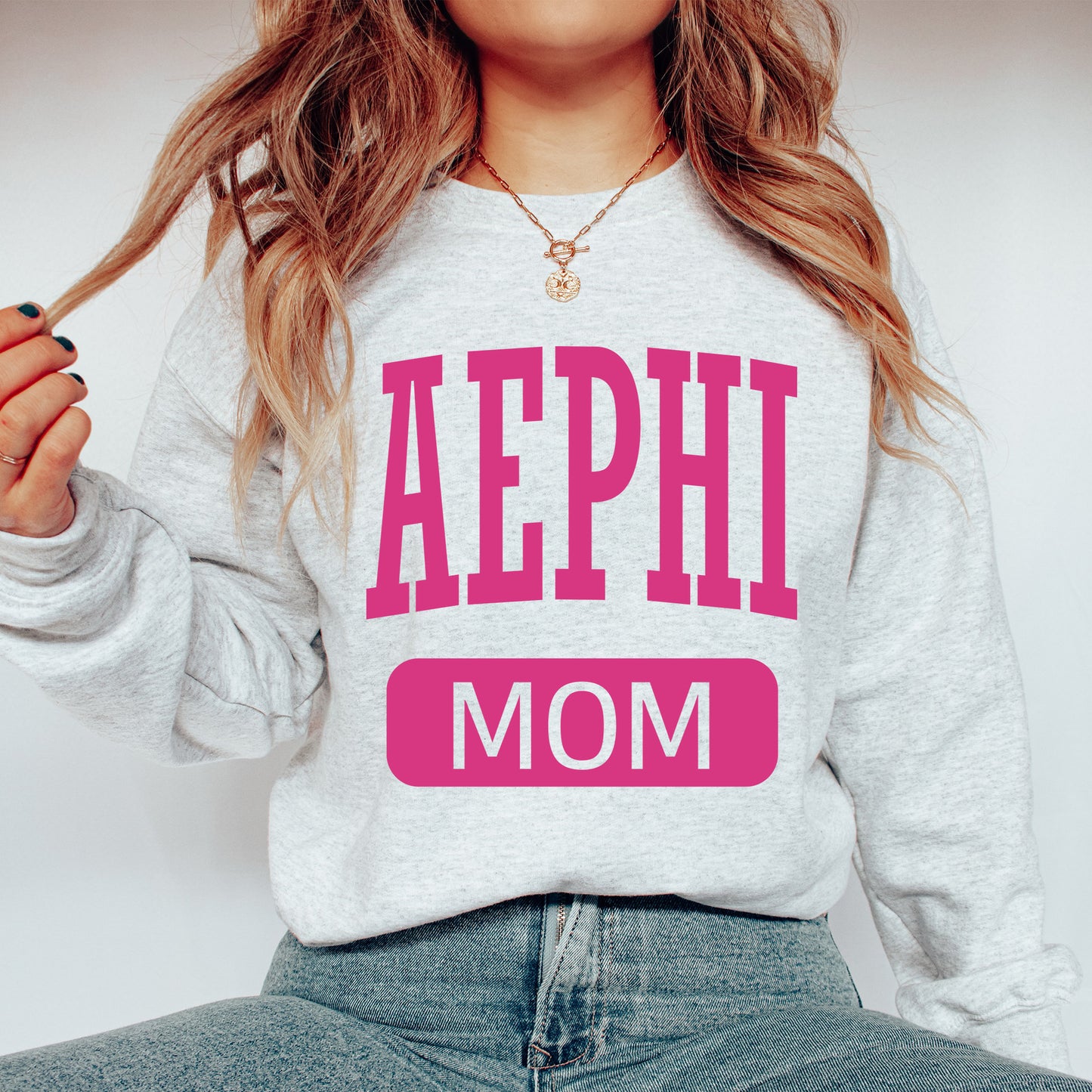 a woman wearing a sweatshirt that says aephi mom