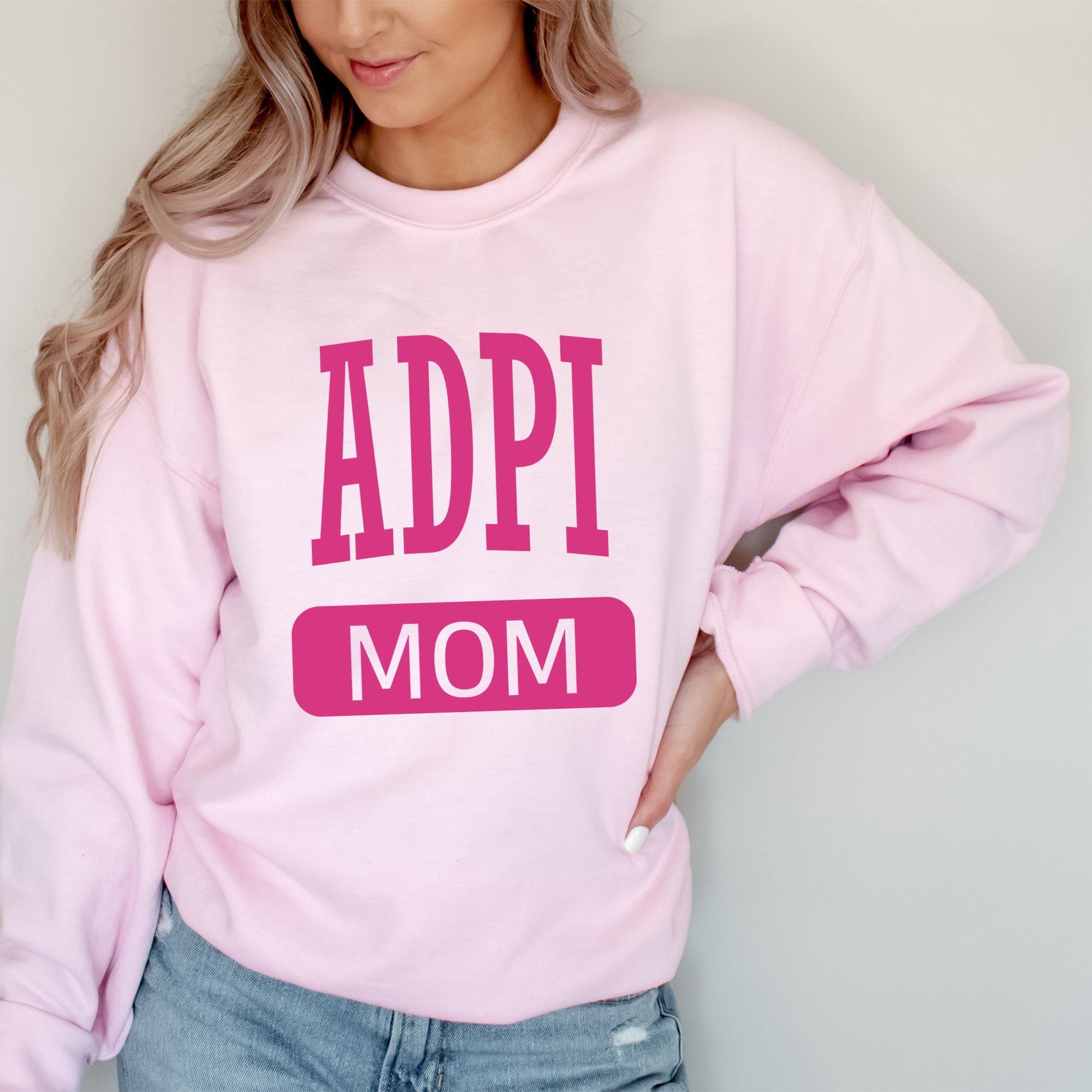 a woman wearing a pink sweatshirt with the words appi mom on it
