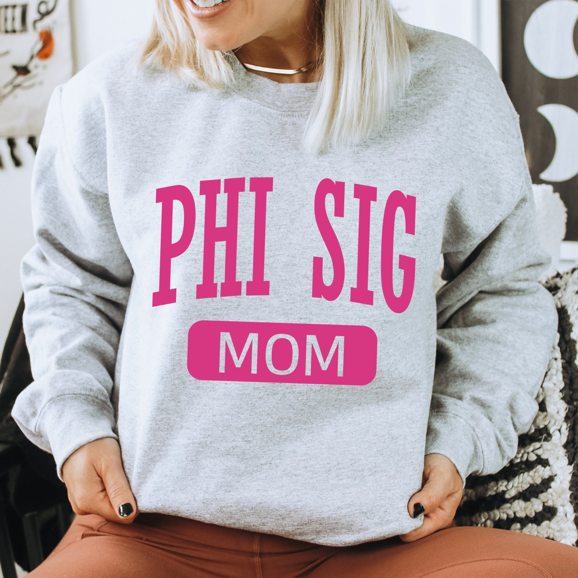 a woman wearing a sweatshirt that says phi sig mom
