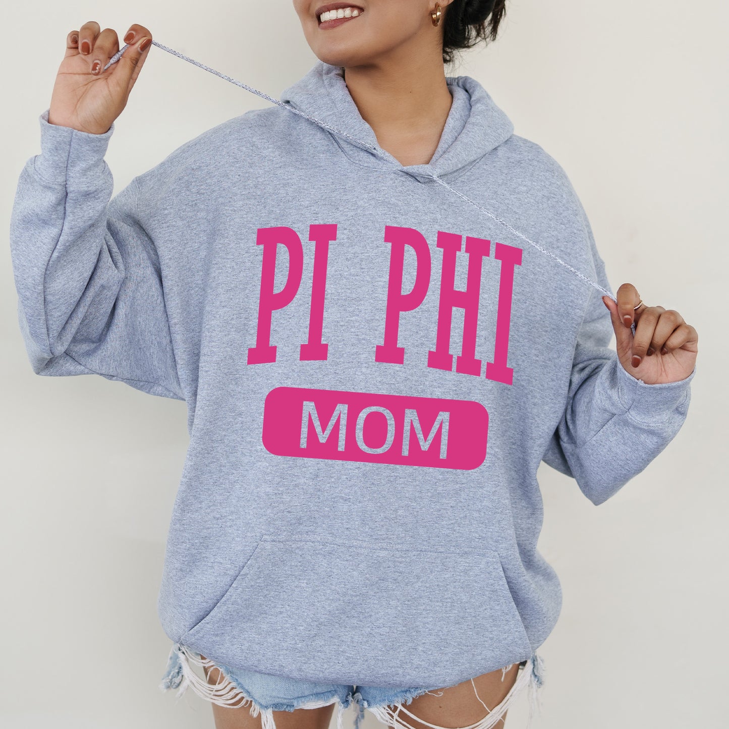 a woman wearing a sweatshirt that says pi phi mom